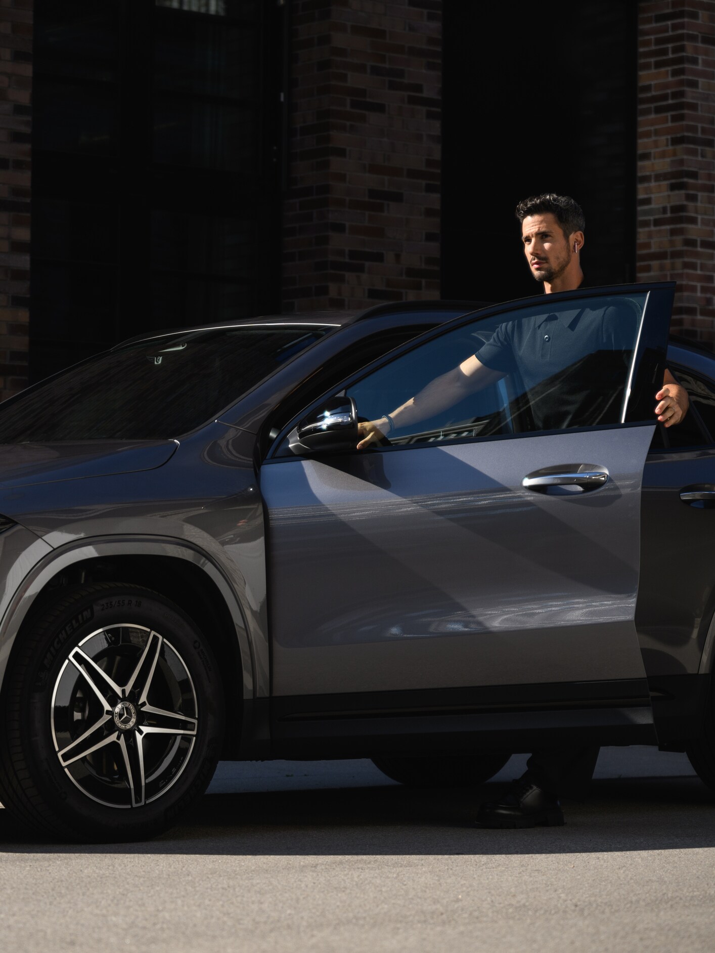 A person opening a car door and standing next to a Mercedes-Benz vehicle.