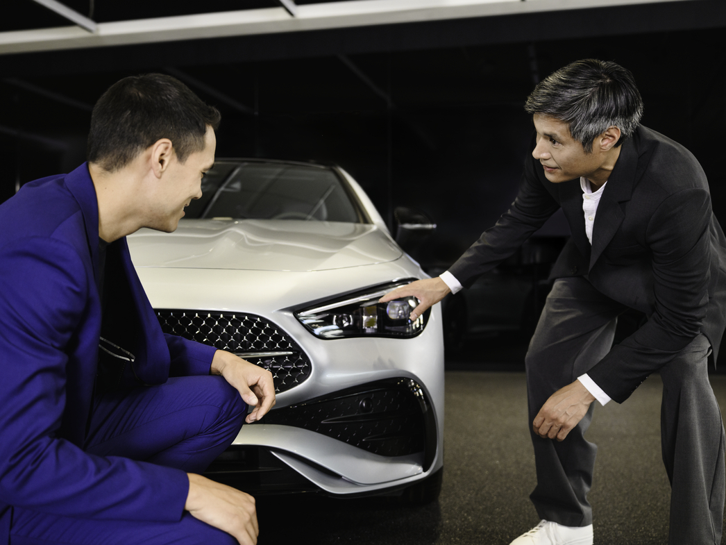 Two people inspecting the front of a Mercedes-Benz car in a showroom Two people inspecting the front of a Mercedes-Benz car in a showroom