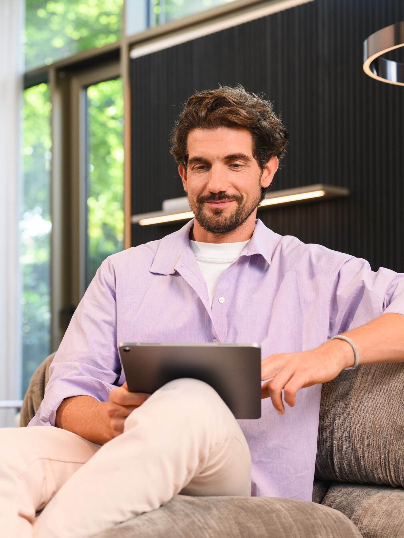 A person sat on a sofa looking at a tablet device.