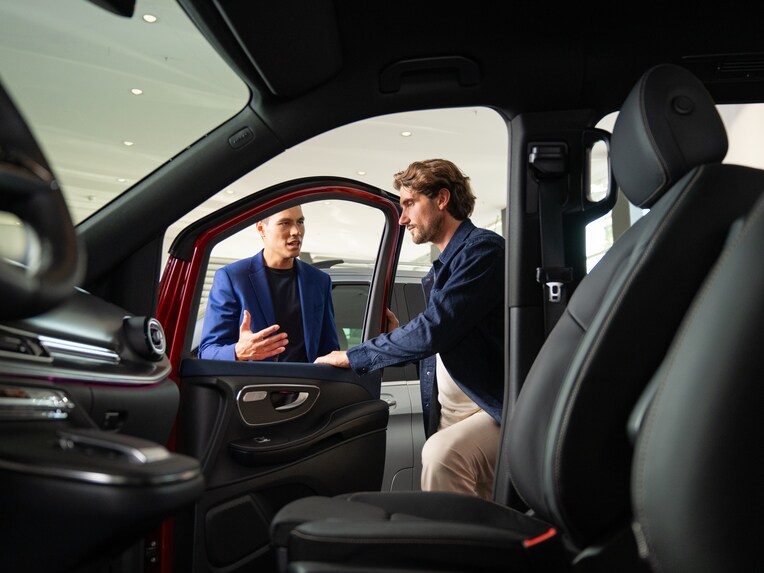 Two people opening a Mercedes-Benz Van door and looking inside.