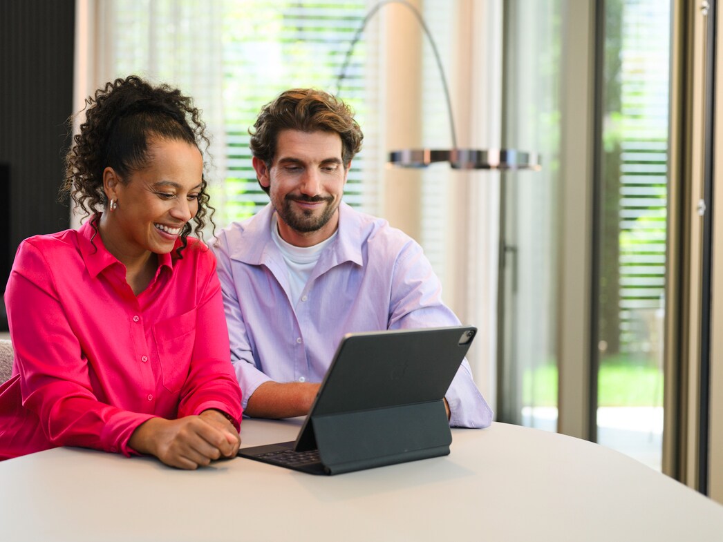 Two people seated at a table using a laptop indoors