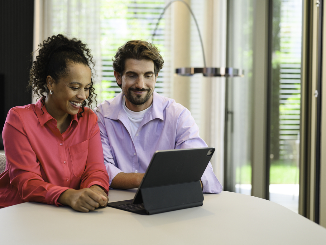 Online Showroom Two people seated at a table using a laptop indoors