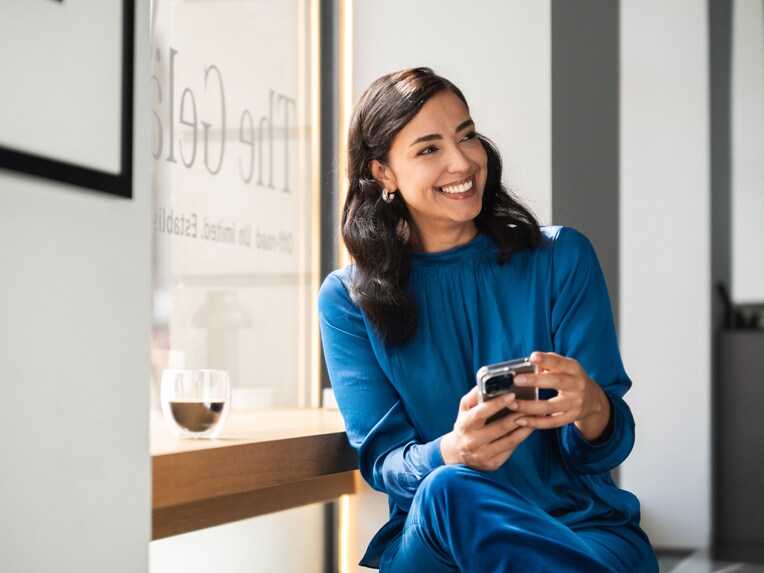 A person smiling and looking at her phone.