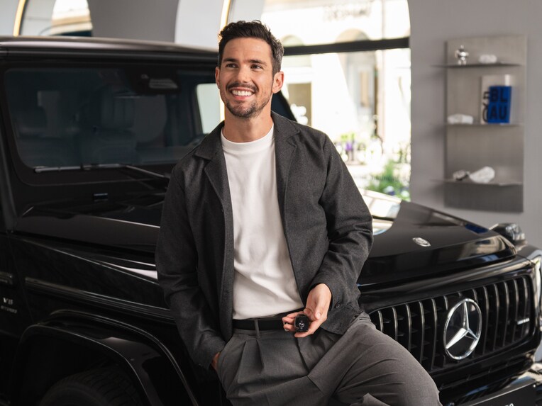 A person smiling in front of a Mercedes-Benz.