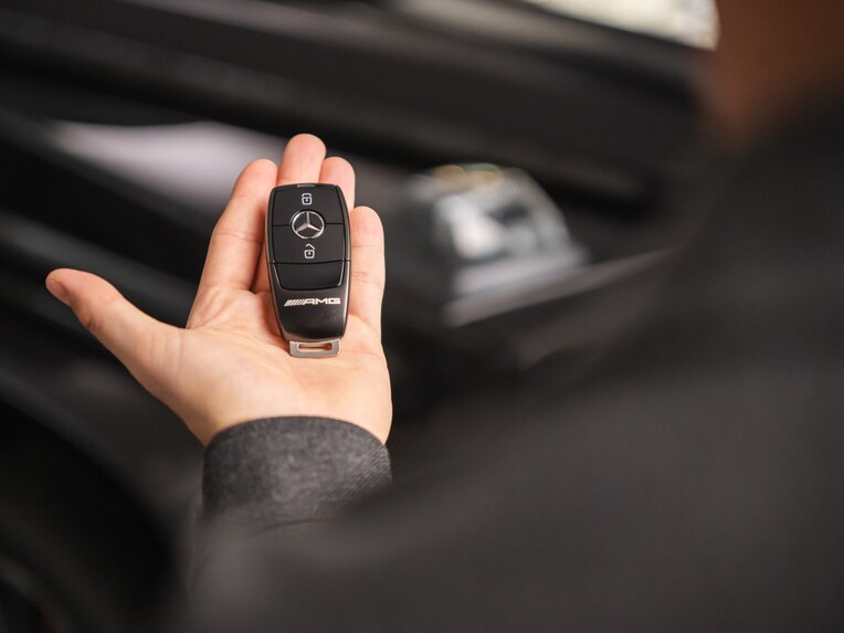 A person holding a Mercedes-Benz key.