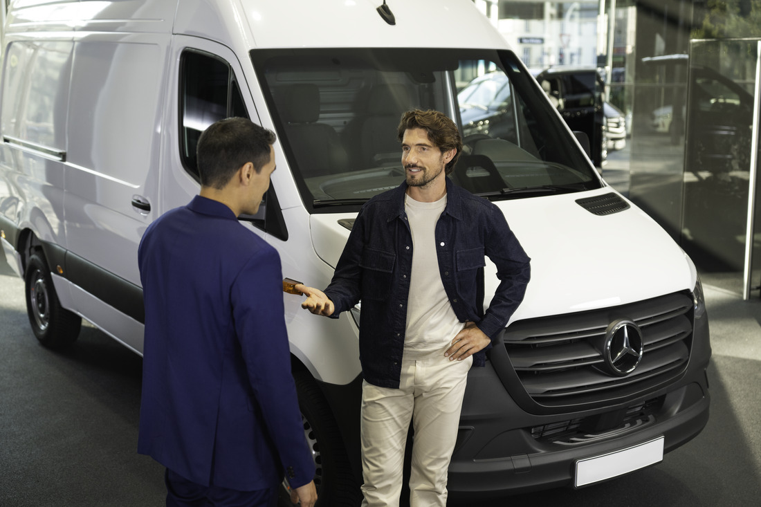 Dealership Consultation | Mercedes-Benz Vans Two people in a Dealership talking in front of a white Mercedes-Benz Sprinter van.