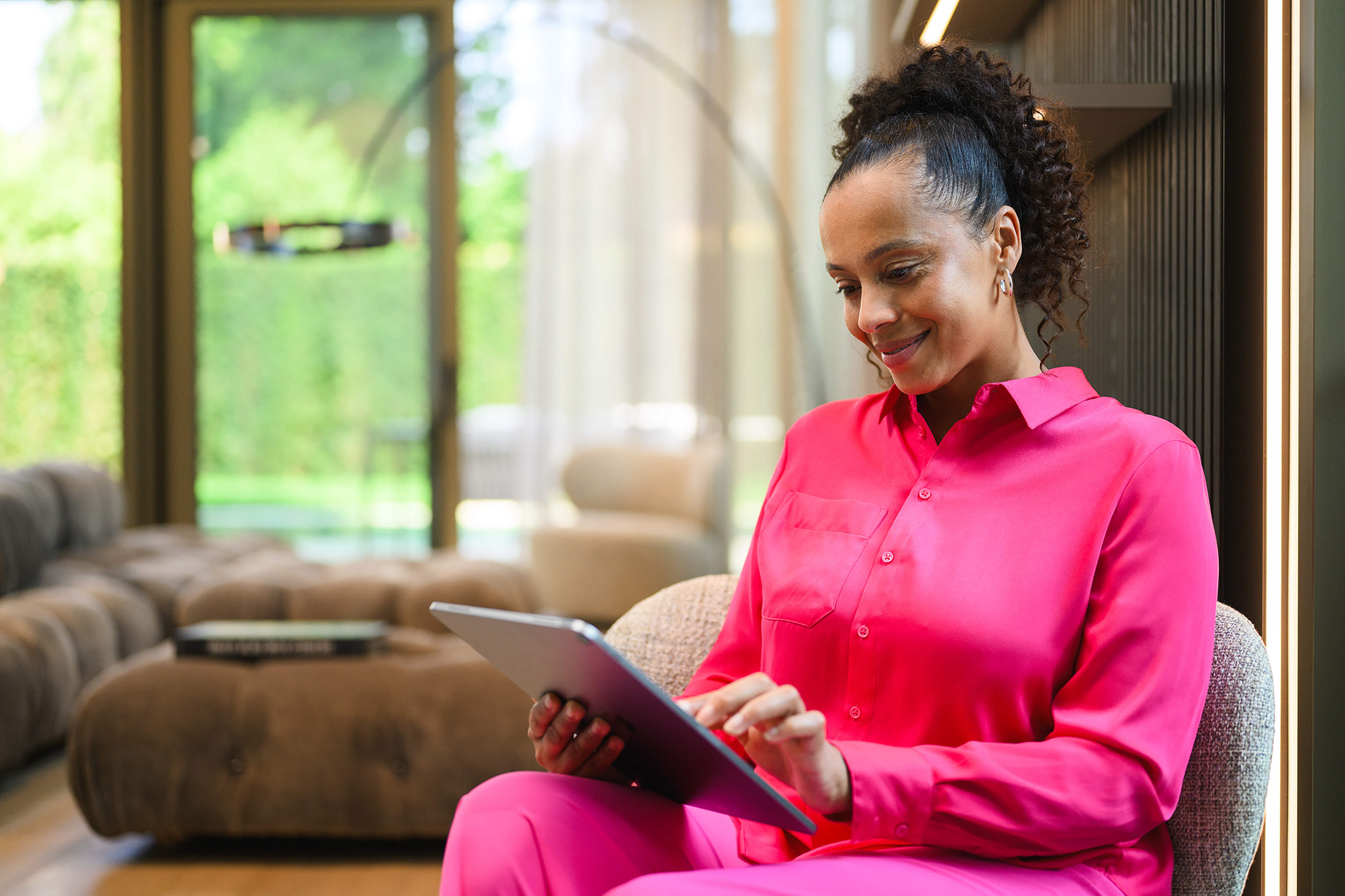 Woman in bright pink clothing using a tablet in a living room Woman in bright pink clothing using a tablet in a living room