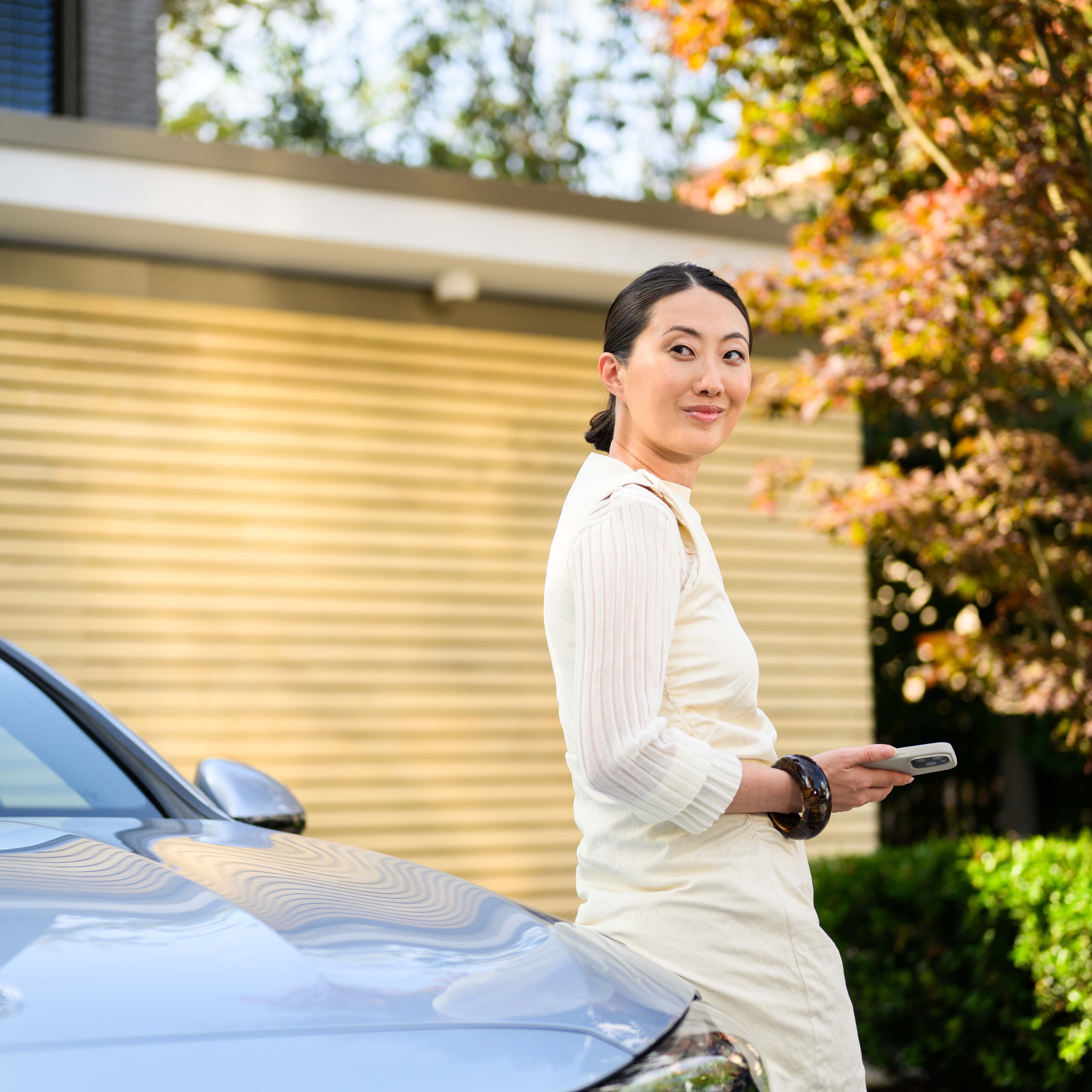 A person leaning against a Mercedes-Benz outside their house.