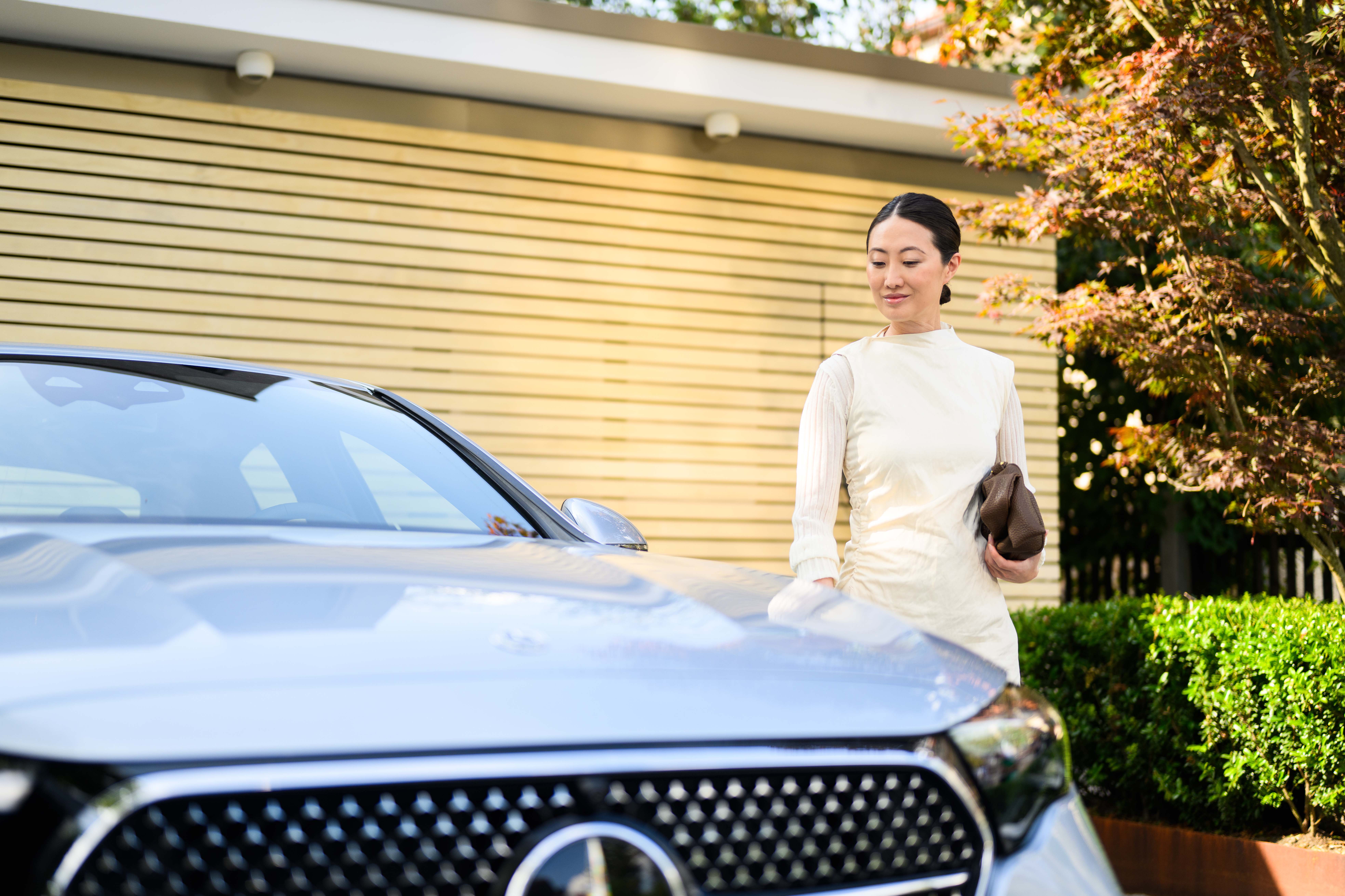 Woman beside a blue Mercedes-Benz outside a home Woman beside a blue Mercedes-Benz outside a home.