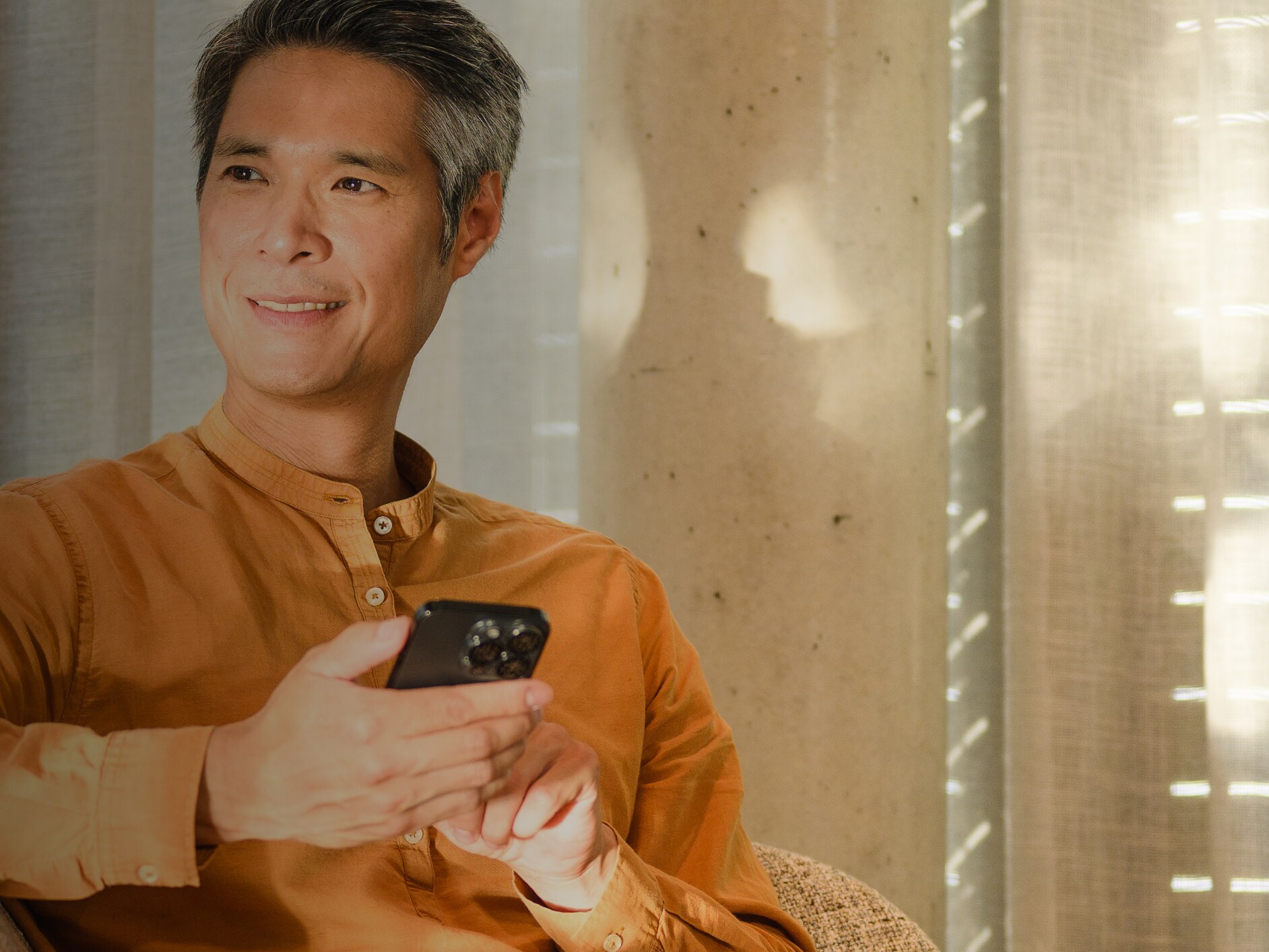Man on a sofa using his phone to fill in a form