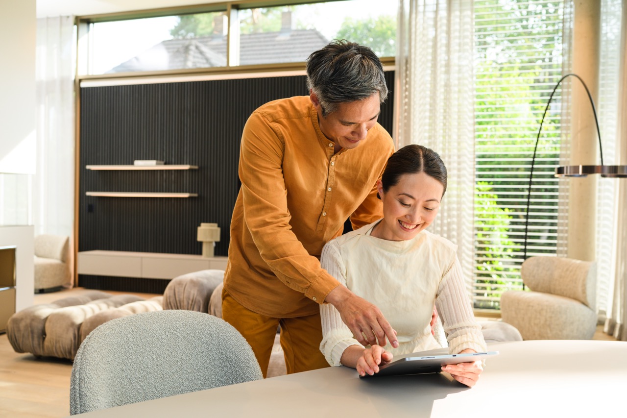 Two people using a tablet together in a modern home setting Two people using a tablet together in a modern home setting