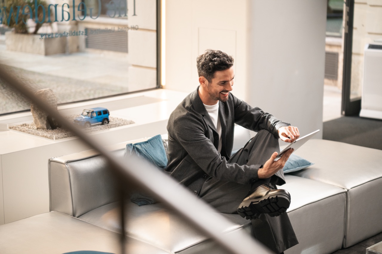 Person using a tablet while seated in a modern lounge area. Person using a tablet while seated in a modern lounge area.