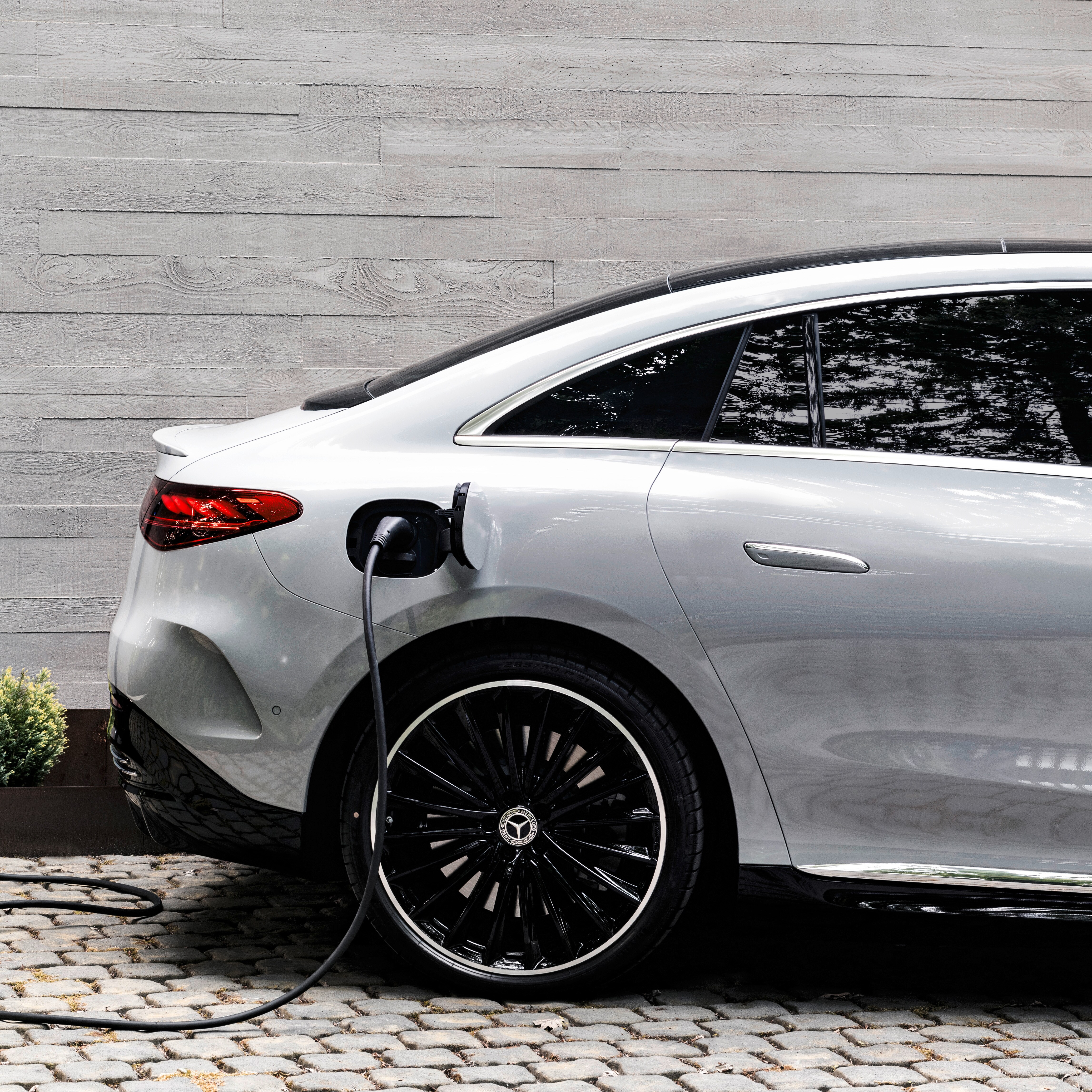 Parked silver Mercedes-Benz  charging against white wooden background