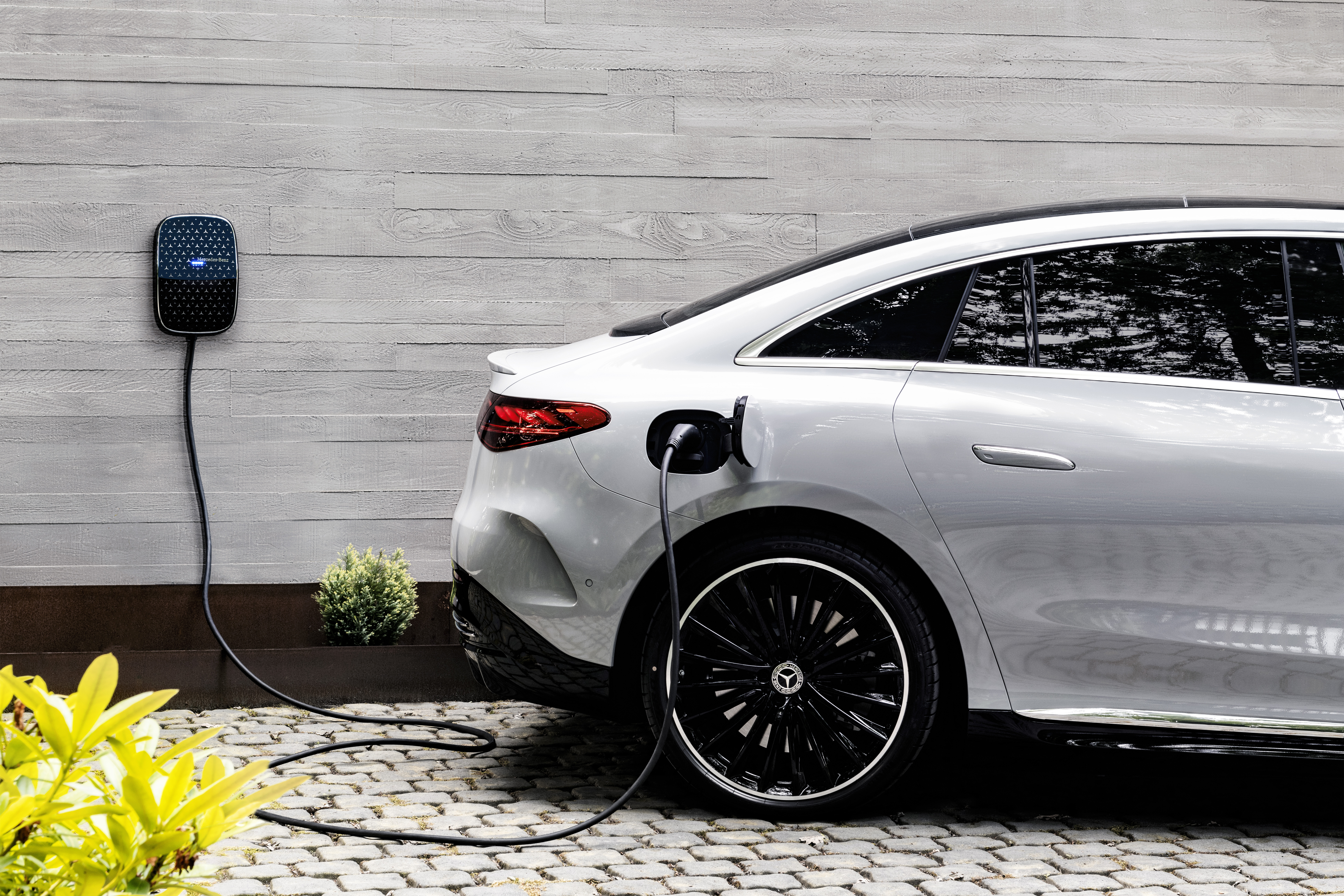 Charging at home | Charging & Services | Mercedes-EQ Parked silver Mercedes-Benz charging against white wooden background