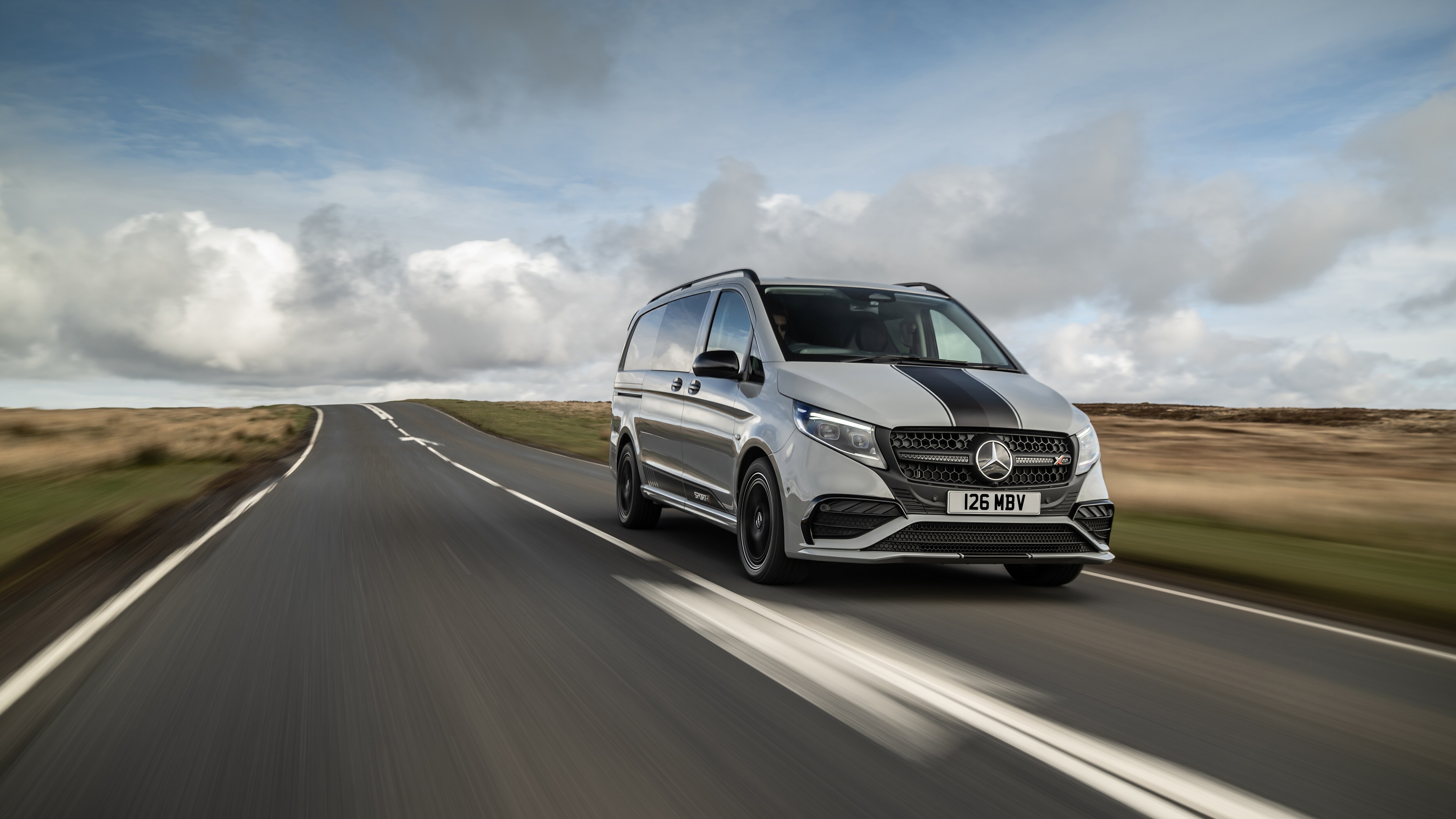 White Mercedes-Benz Vito Panel Van parked by modern concrete structure.