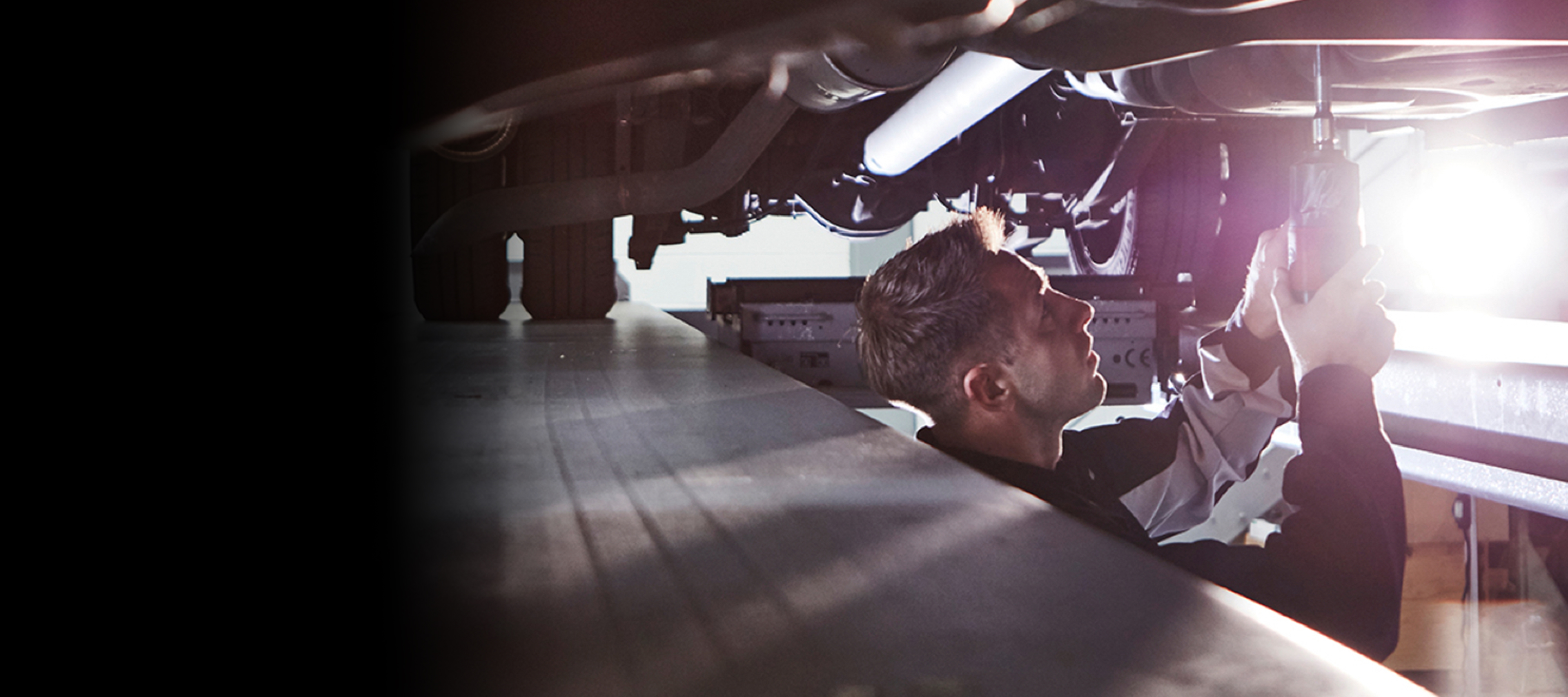 Mercedes-Benz | Services Overview | Electric Van Services Three employees standing in front of a silver Mercedes-Benz eSprinter with charging cable attached.