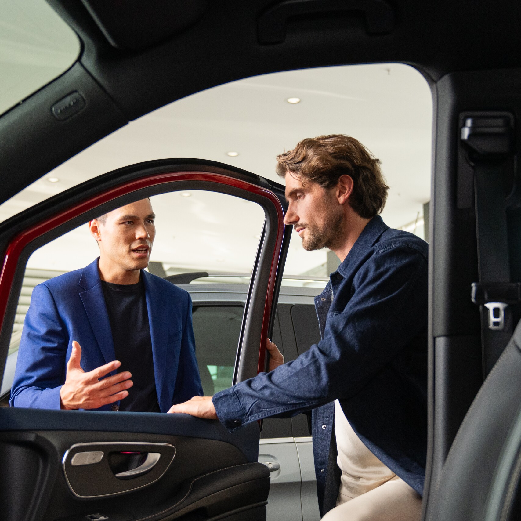 Two people opening a Mercedes-Benz Van door and looking inside.