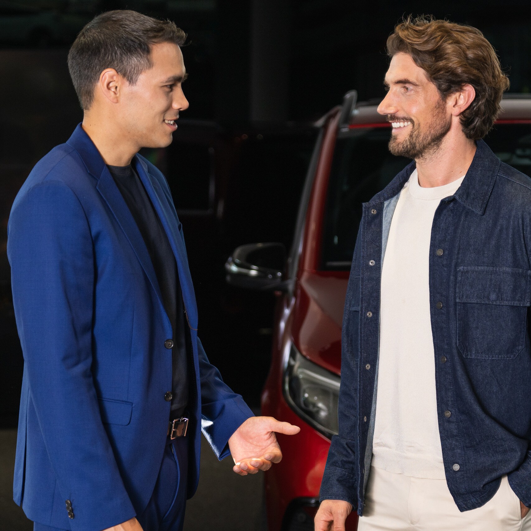 Two people talking to each other in front of two Mecedes-Benz vans.