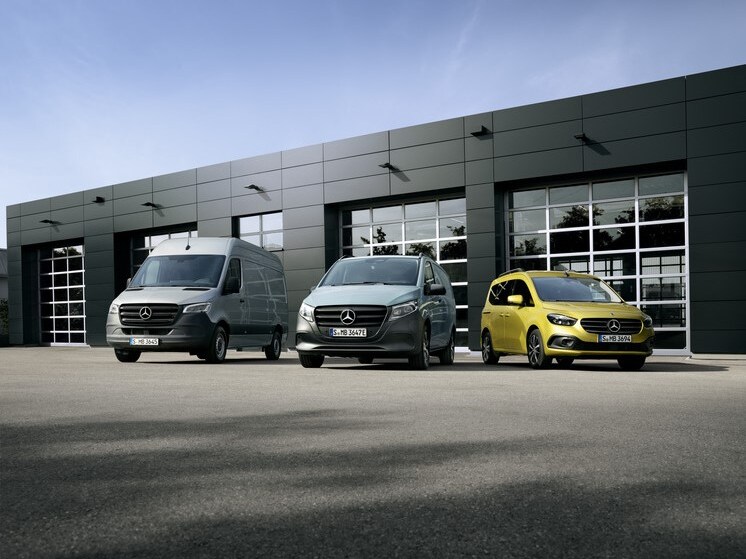 A grey Sprinter, a light grey Vito, and a yellow Citan parked in front of a modern building.