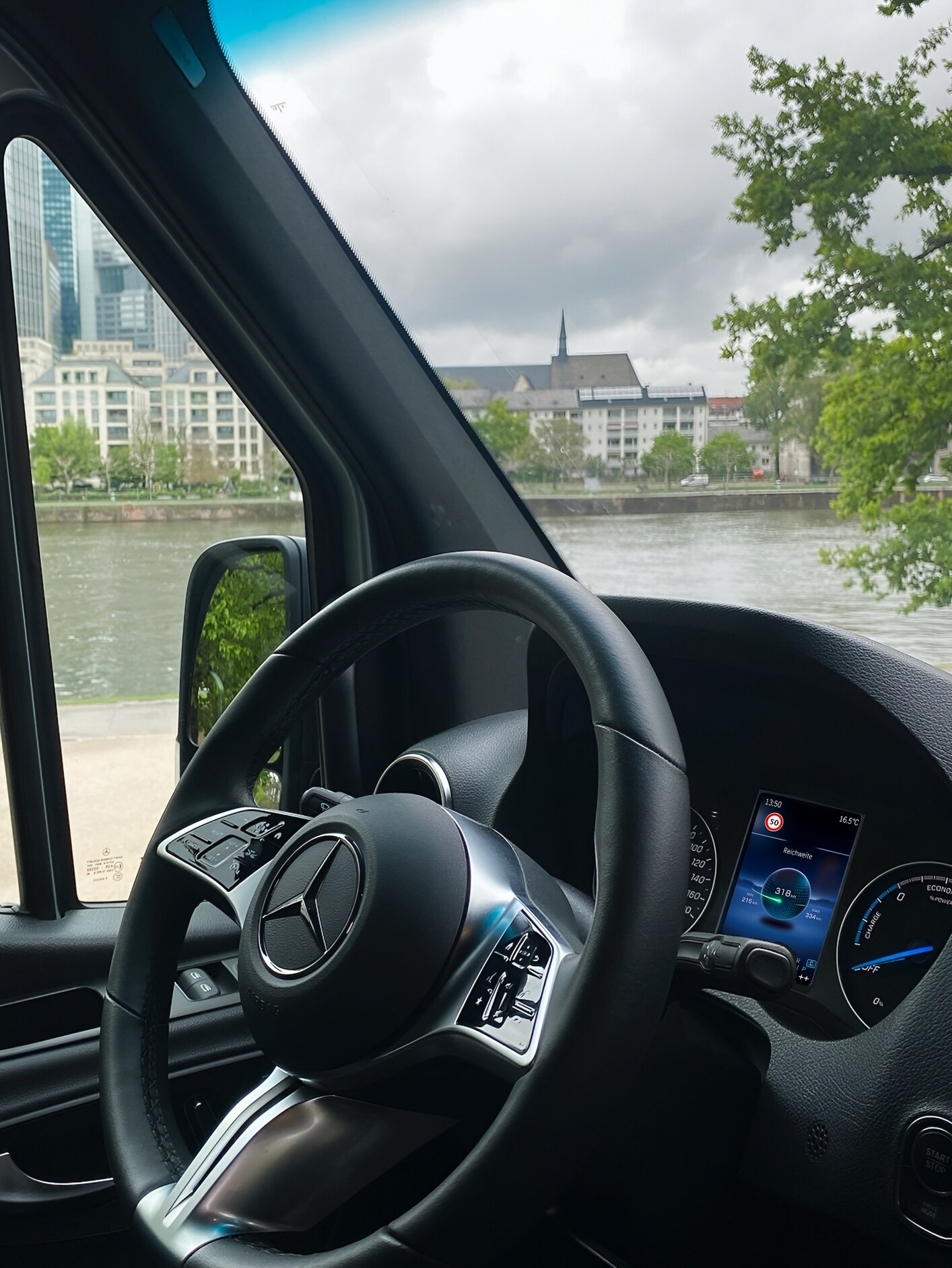 A view from the driver's seat showing the steering wheel and a city river and skyline through the window.