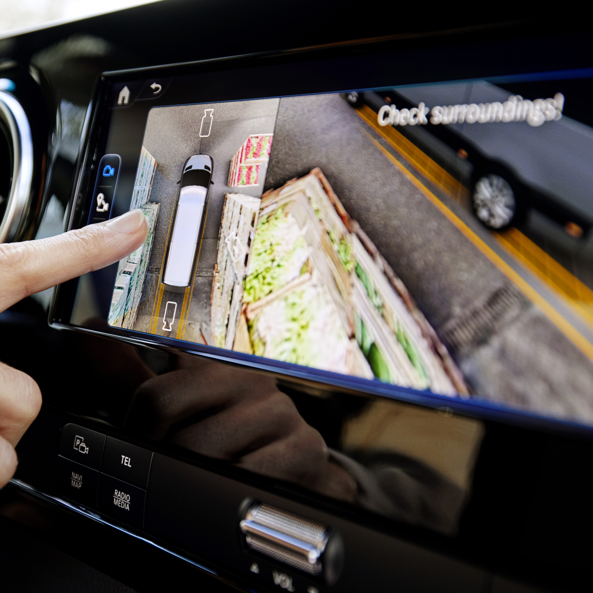 A Van's 360-degree Camera System | Mercedes-Benz Vans A finger on a vehicle infotainment screen showing a 360-degree top-down camera view.