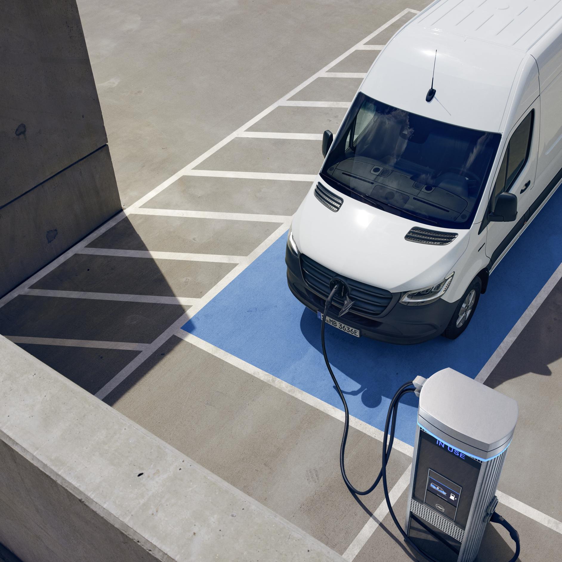 A White Mercedes-Benz eSprinter Van Charging | Mercedes-Benz Vans An elevated view of a white Mercedes-Benz van parked and charging at an electric vehicle charging station.