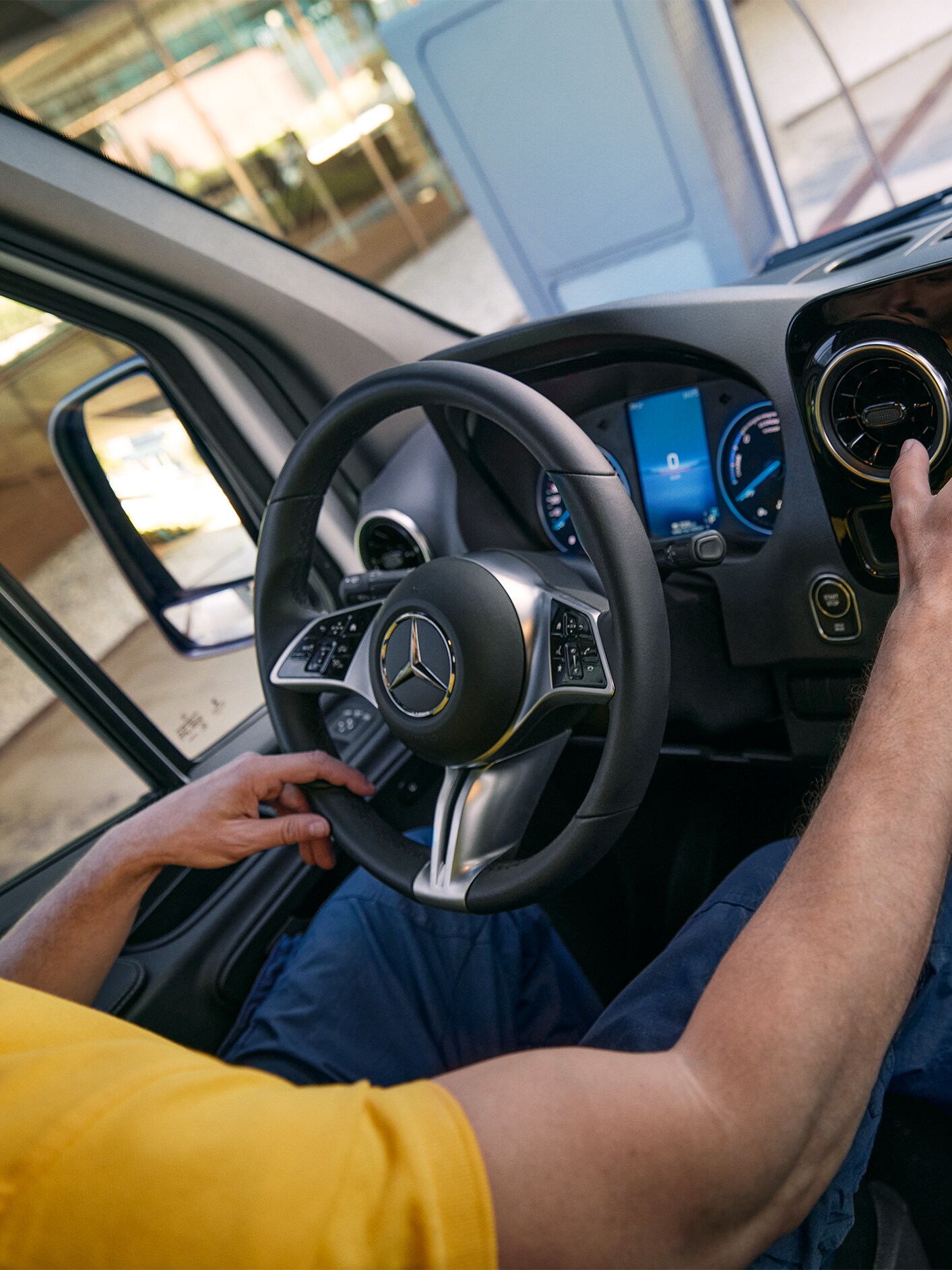A person in a yellow shirt using the MBUX multimedia in a Mercedes-Benz van.