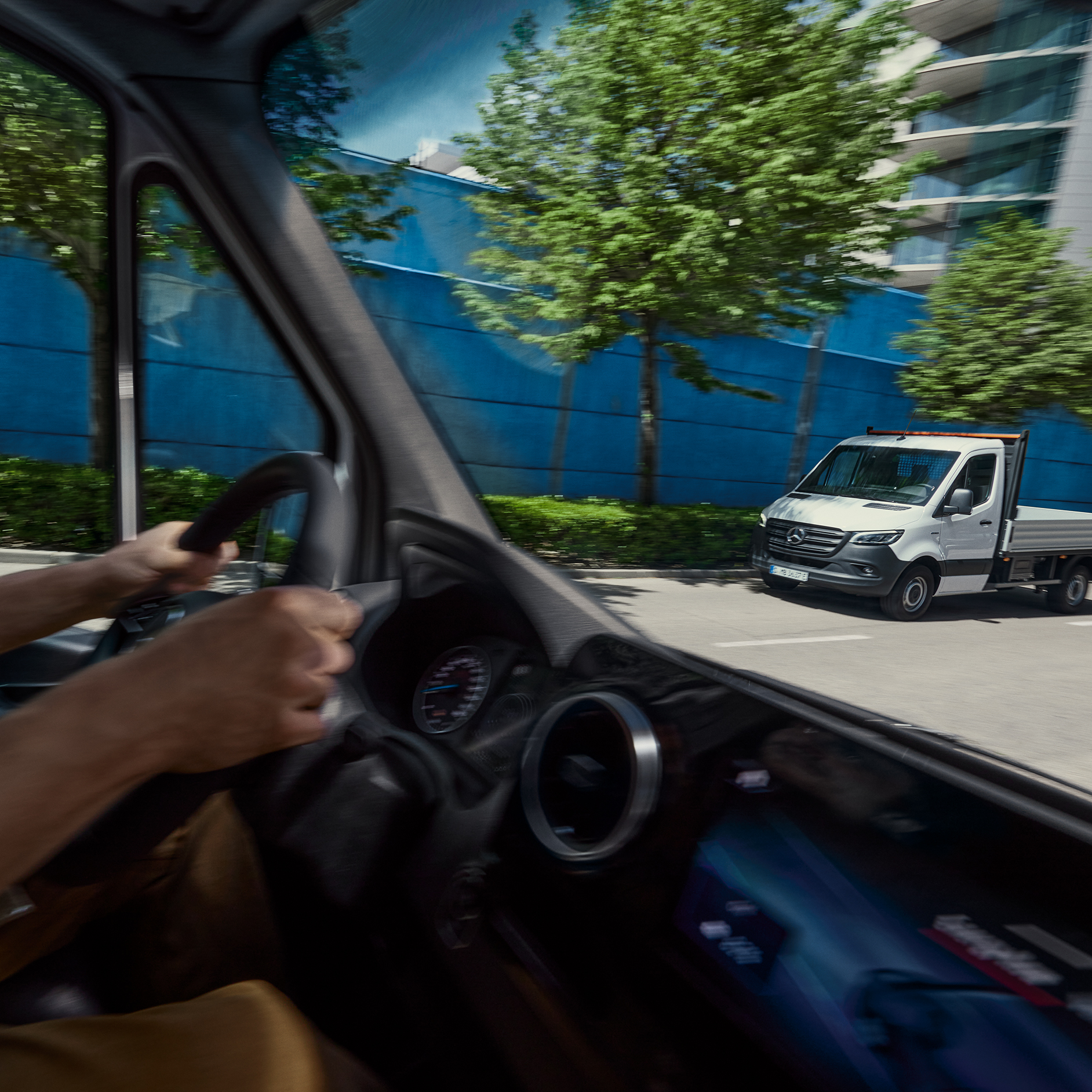 Driver's View from Inside a Van | Mercedes-Benz Vans The interior of a Mercedes-Benz van from the driver's perspective with a Sprinter Chassis Cab parked outside.