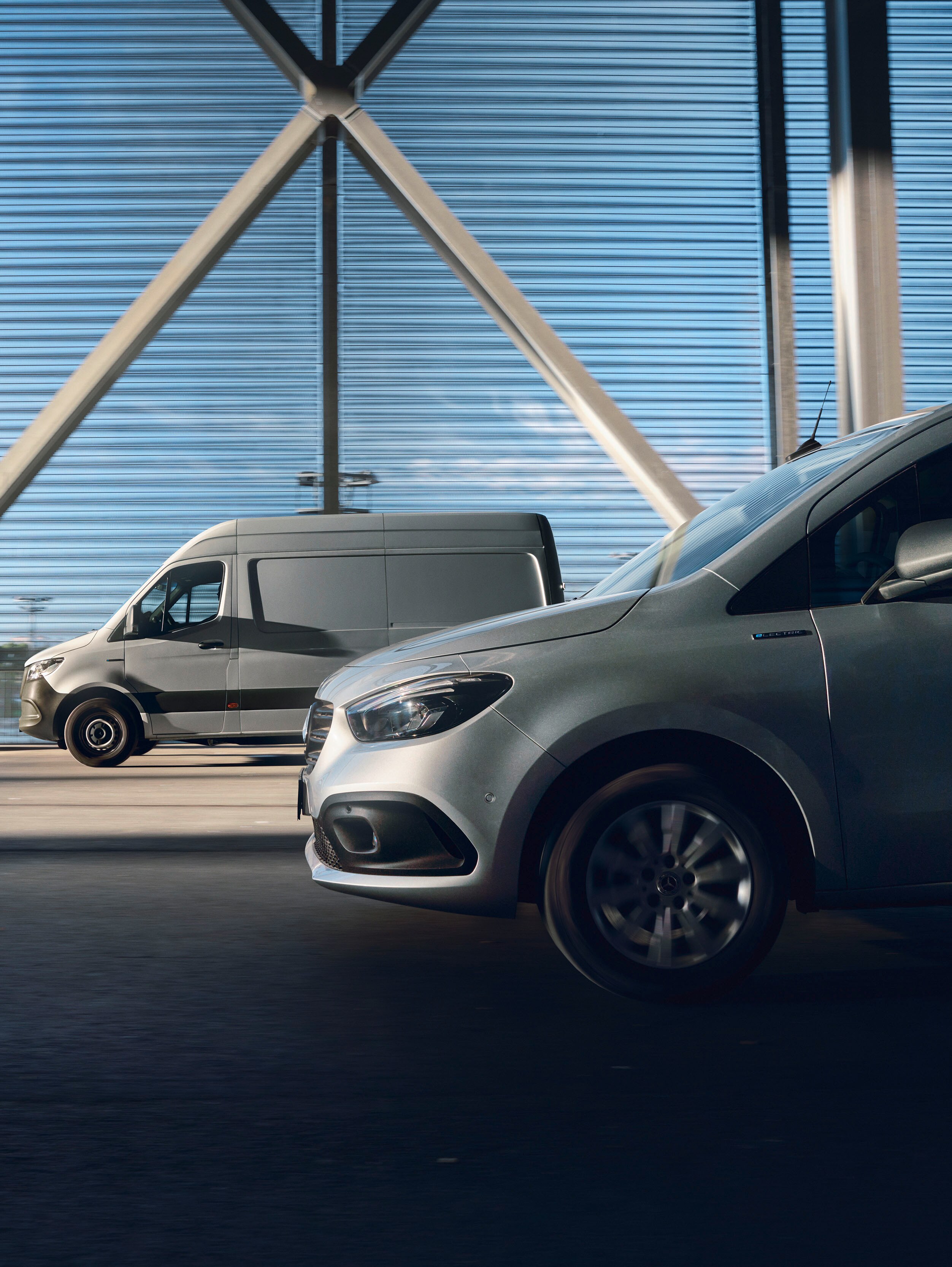 Two Mercedes-Benz commercial vehicles: a silver Citan van in the foreground and a grey Sprinter in the background.