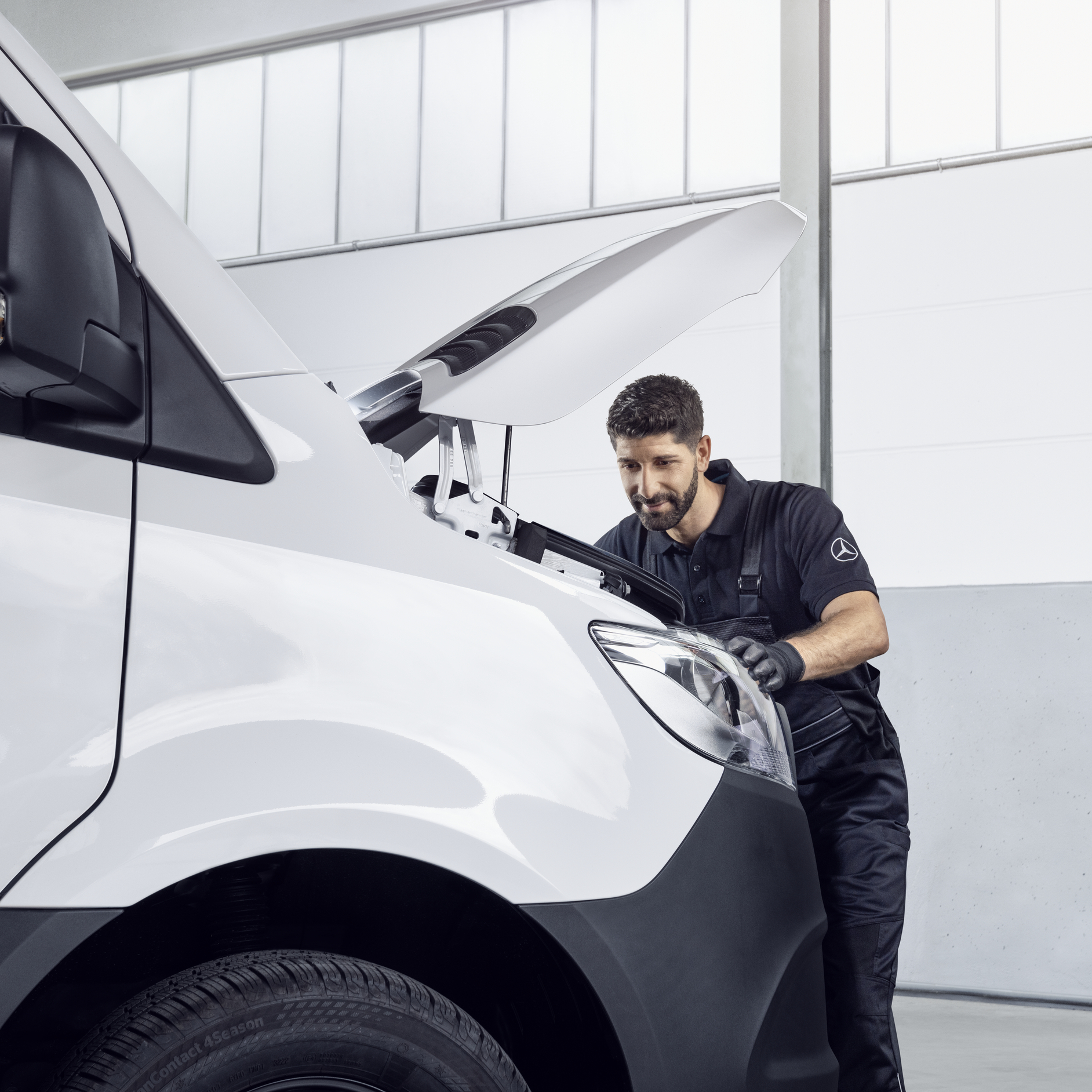 Service Inspection | Mercedes-Benz Vans A technician inspecting the engine bay of a white Mercedes-Benz van with the bonnet open.