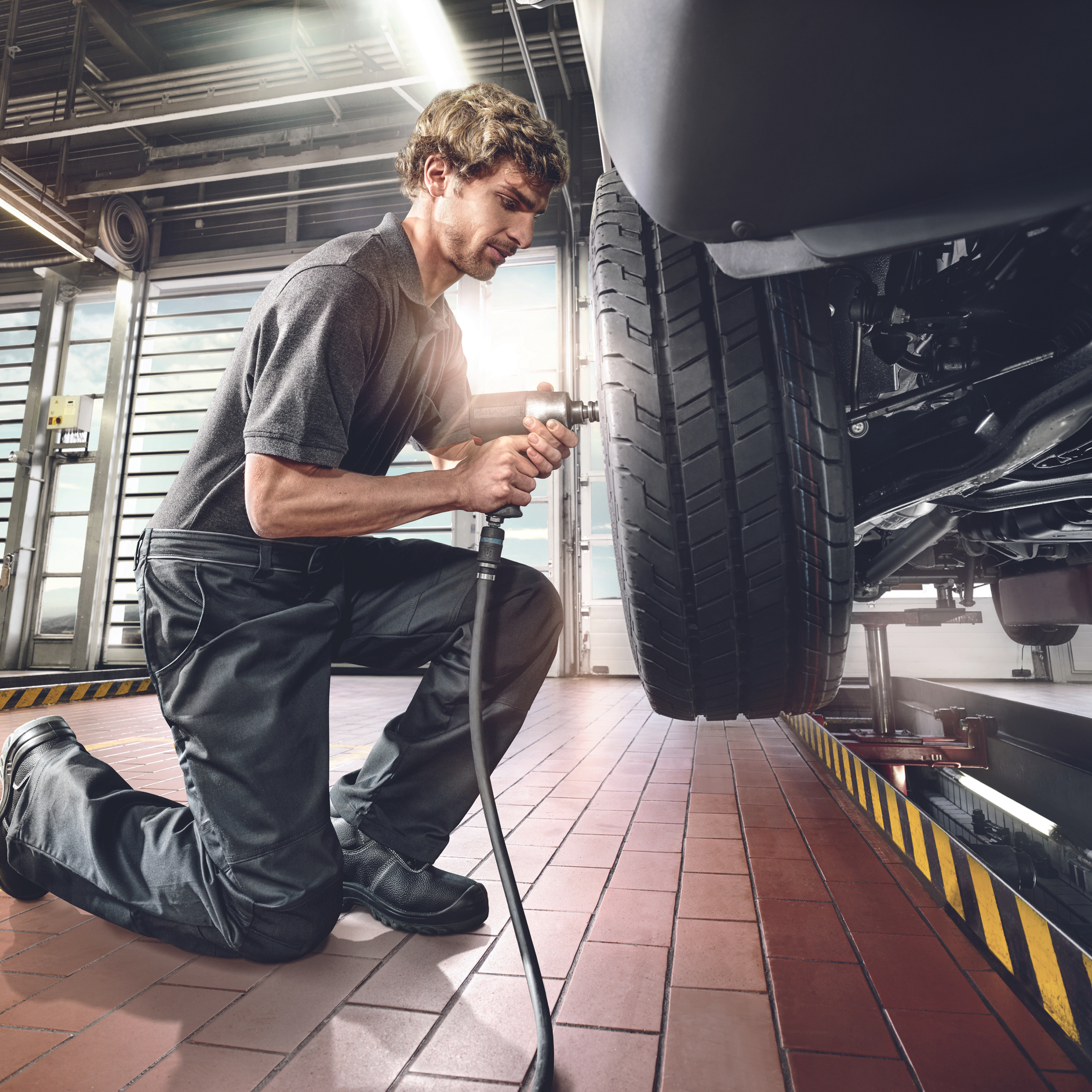 Van Tyre Replacement | Mercedes-Benz Vans A technician using an impact wrench to change a tyre on a vehicle raised on a lift
