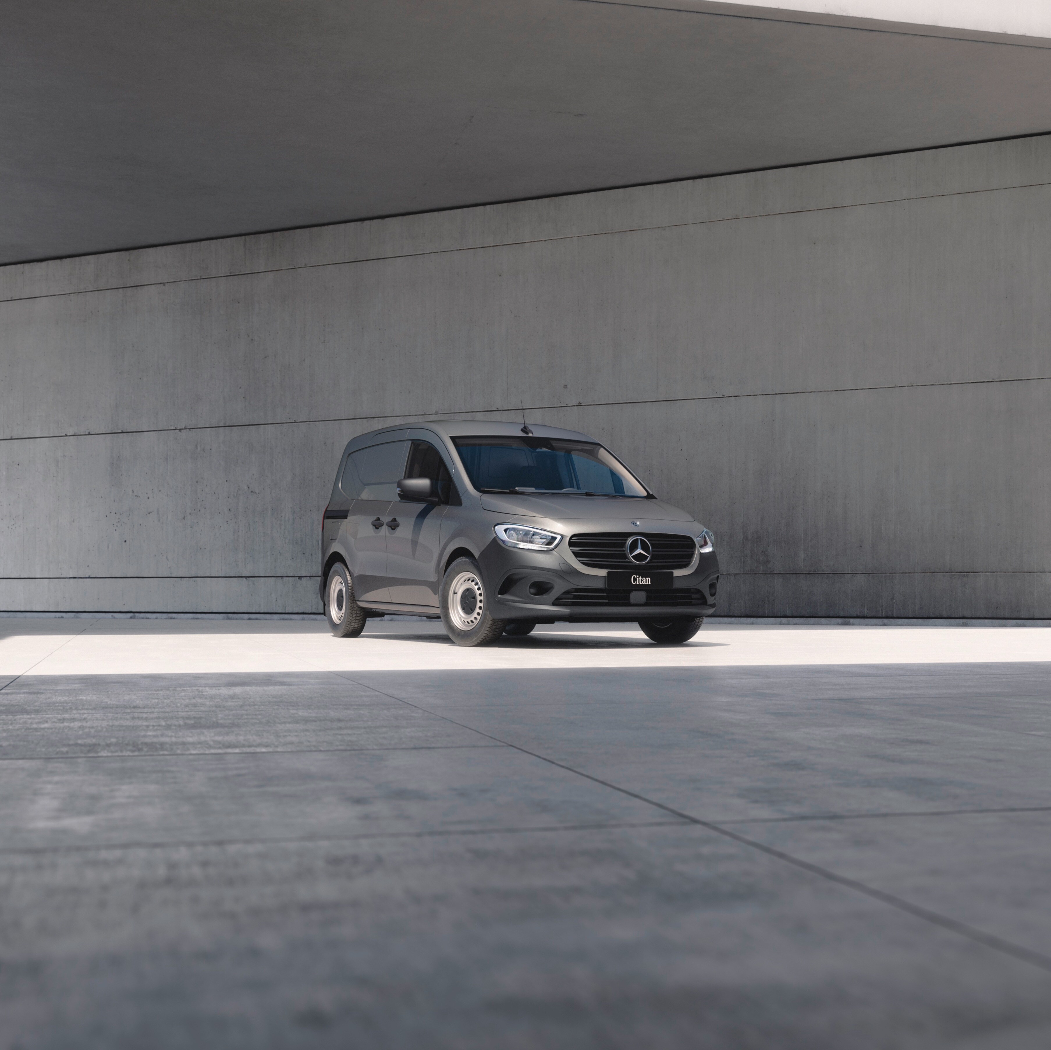 Birdseye view of three Mercedes-Benz panel vans – a grey Citan, a white Vito and a dark Blue Sprinter – under a bridge in an urban setting.