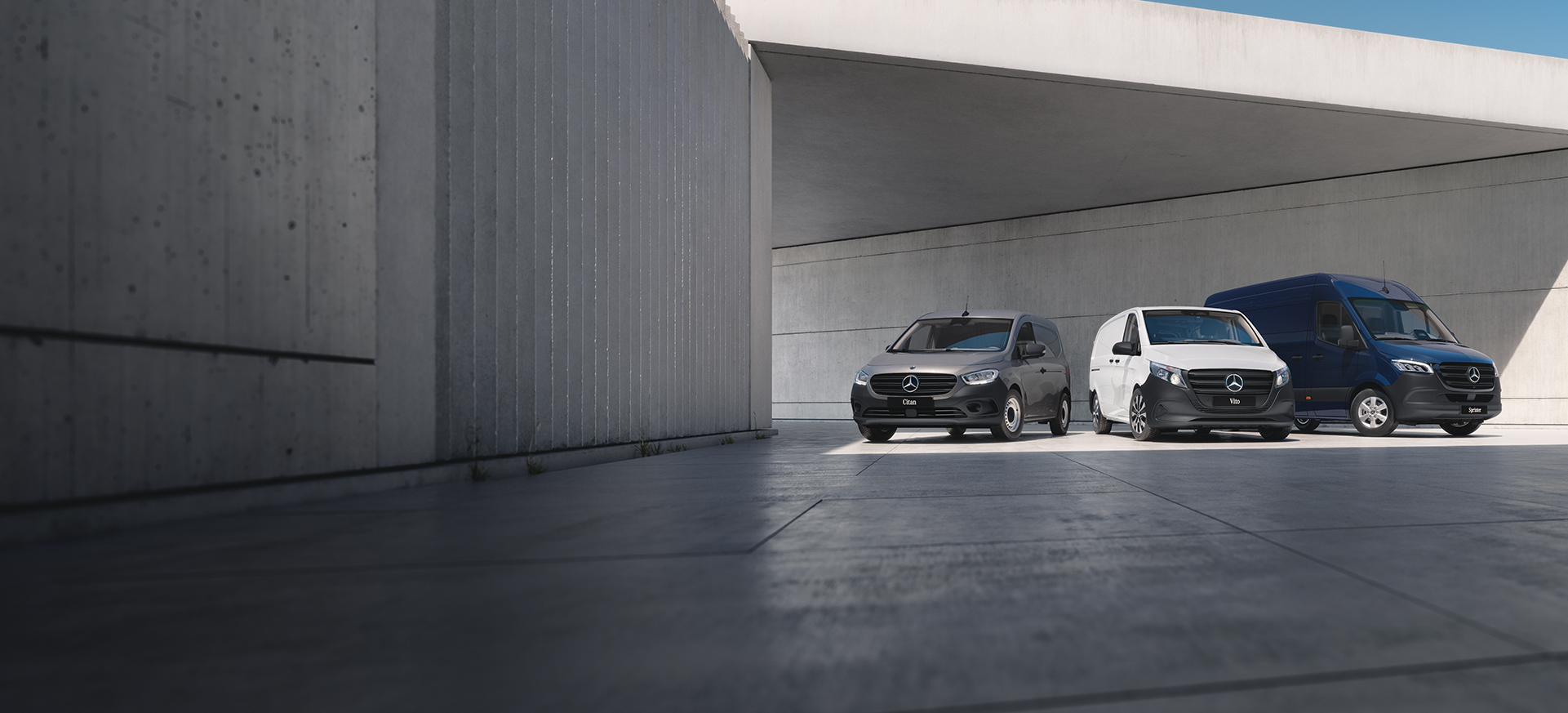 Three Mercedes-Benz panel vans – a grey Sprinter, a blue Vito, and a yellow Citan – positioned on a rooftop with a cityscape backdrop.