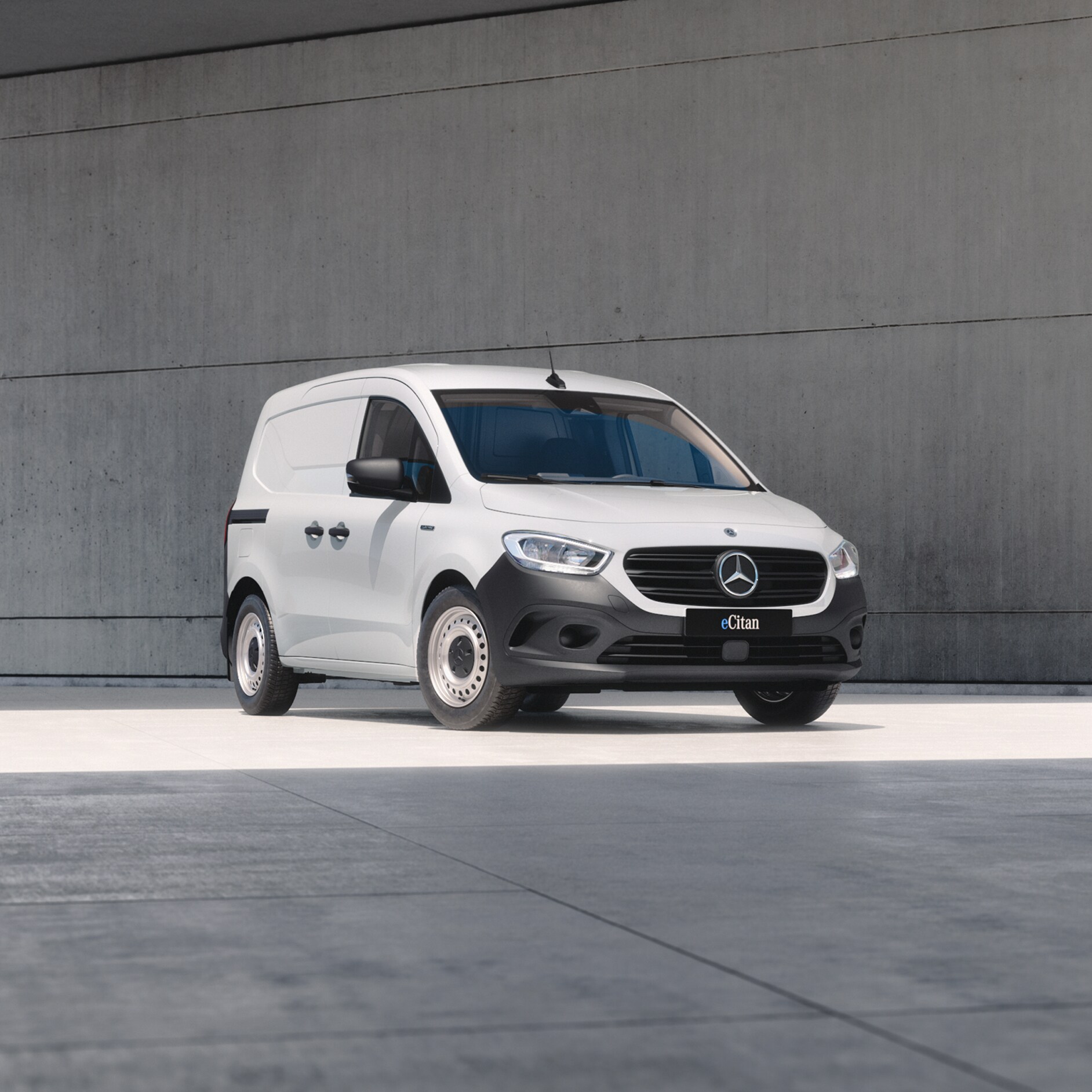 White Mercedes-Benz eCitan Panel Van parked by modern concrete structure.