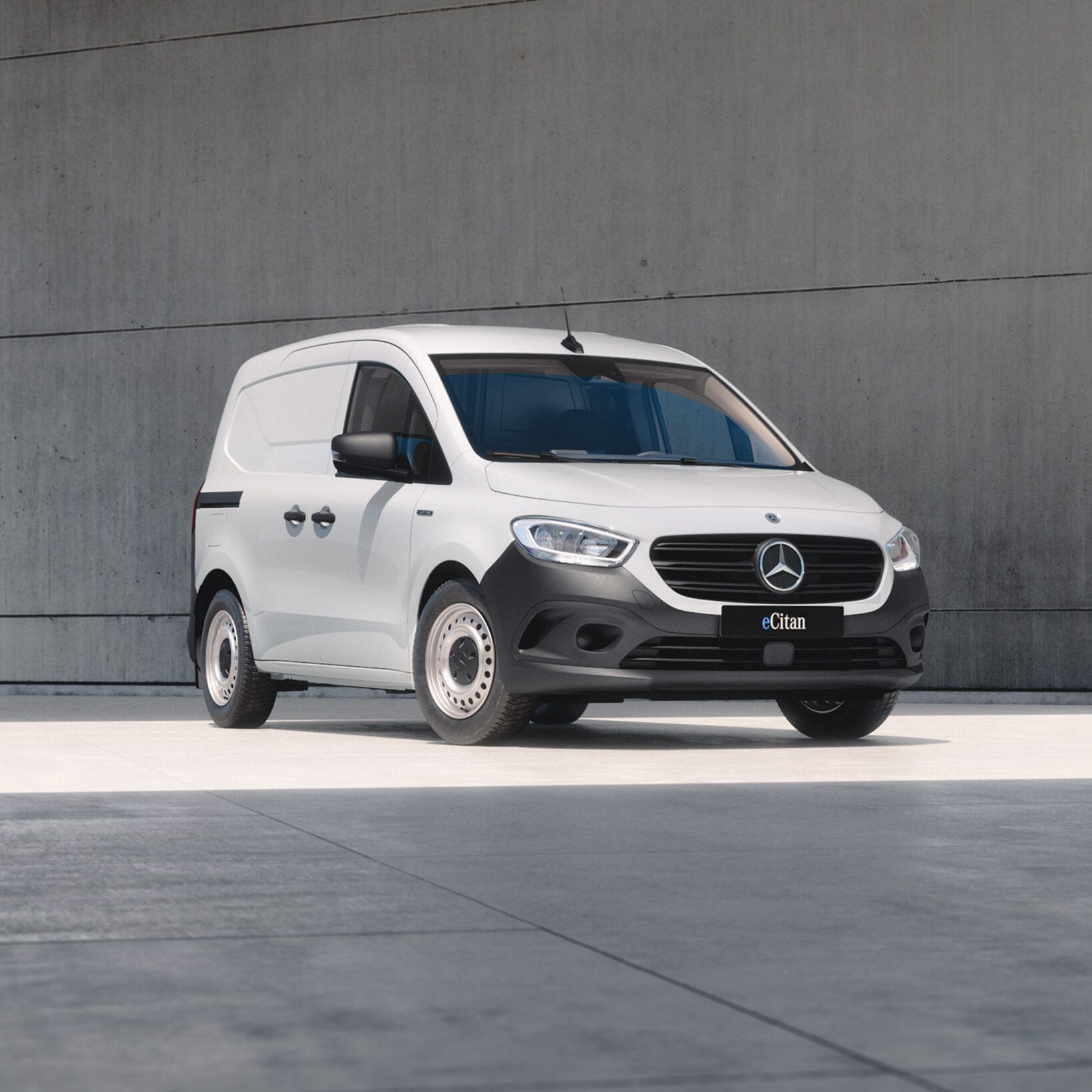 White Mercedes-Benz eCitan Panel Van parked by modern concrete structure.