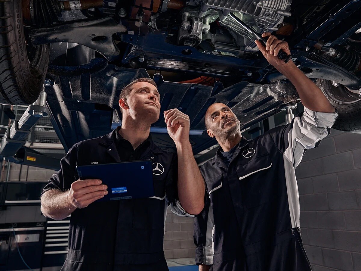 A technician in black uniform examining an air filter in the cabin of a blue Mercedes-Benz van.