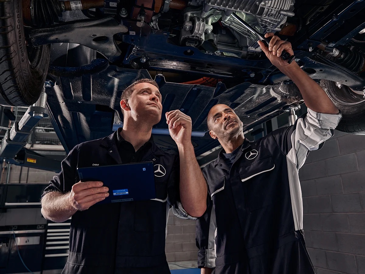 Service Technician | Mercedes-Benz Vans A technician in black uniform examining an air filter in the cabin of a blue Mercedes-Benz van.