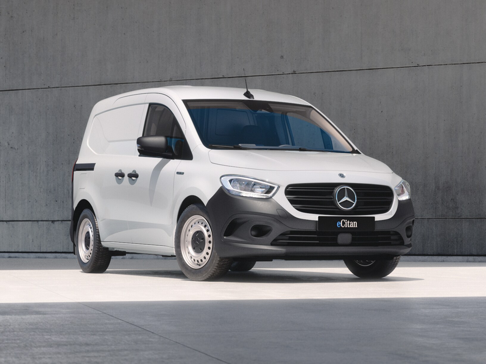 White Mercedes-Benz eCitan Panel Van parked by modern concrete structure.
