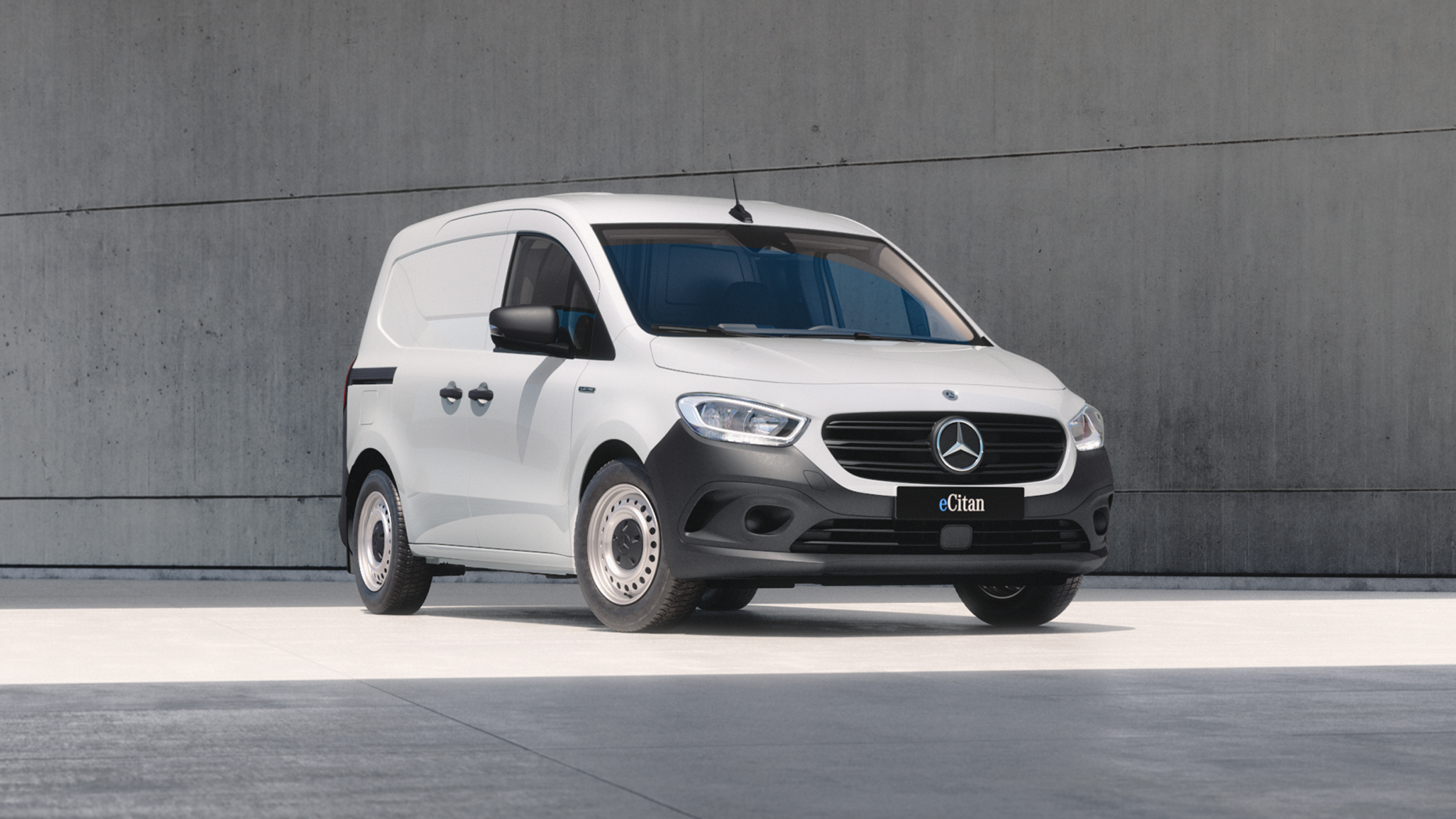 eCitan Panel Van | Mercedes-Benz Vans White Mercedes-Benz eCitan Panel Van parked by modern concrete structure.