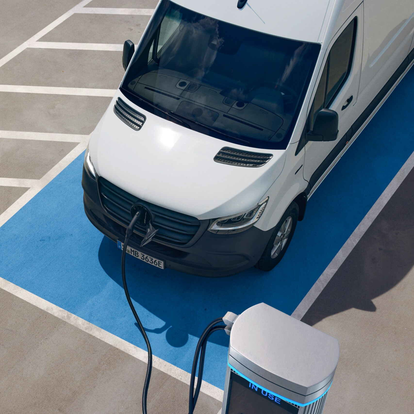 Close-up of the bonnet of a Mercedes-Benz eSprinter, showing the van plugged in and charging in a parking space.