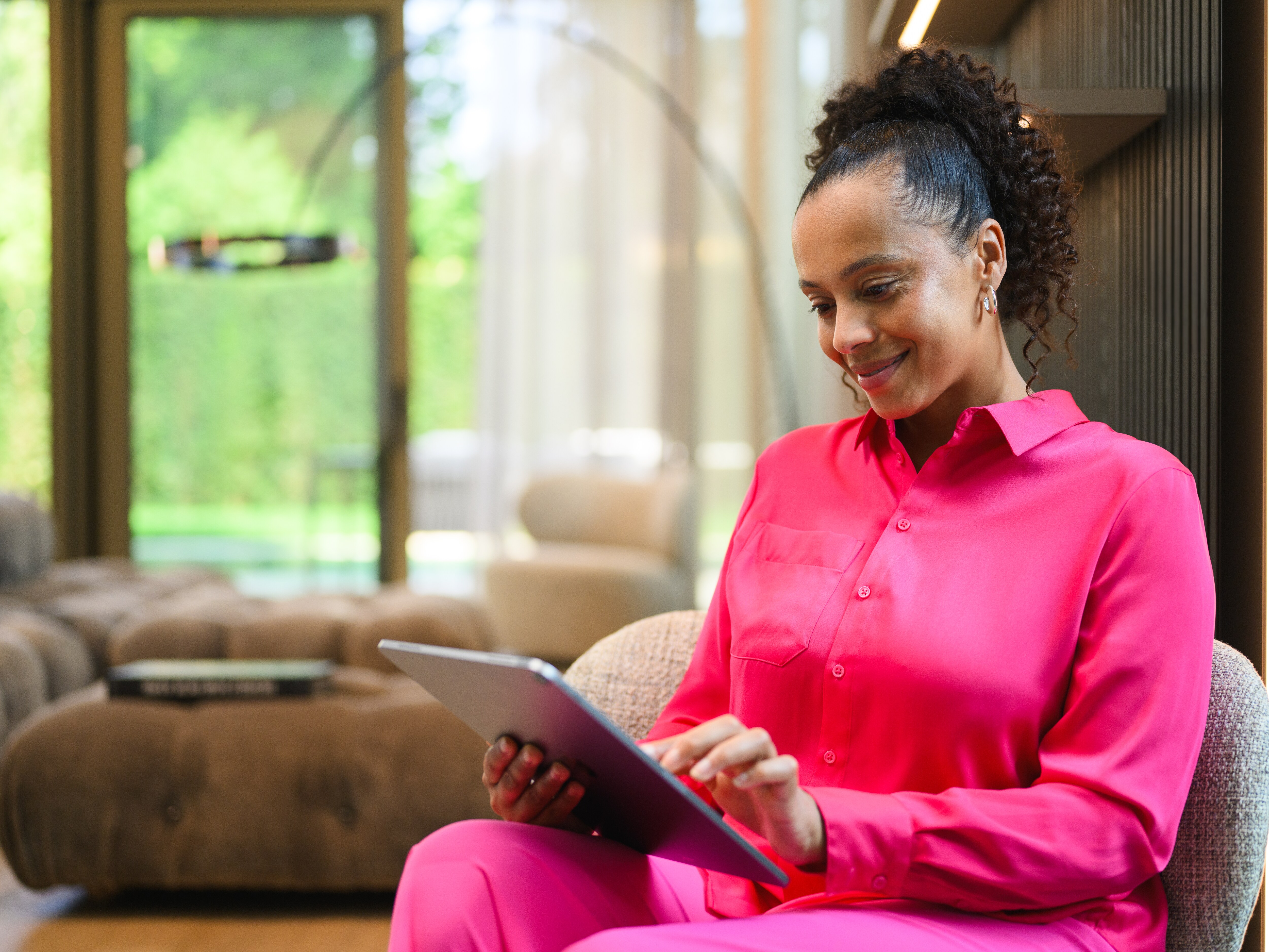 A person at home looking at a tablet device and smiling.