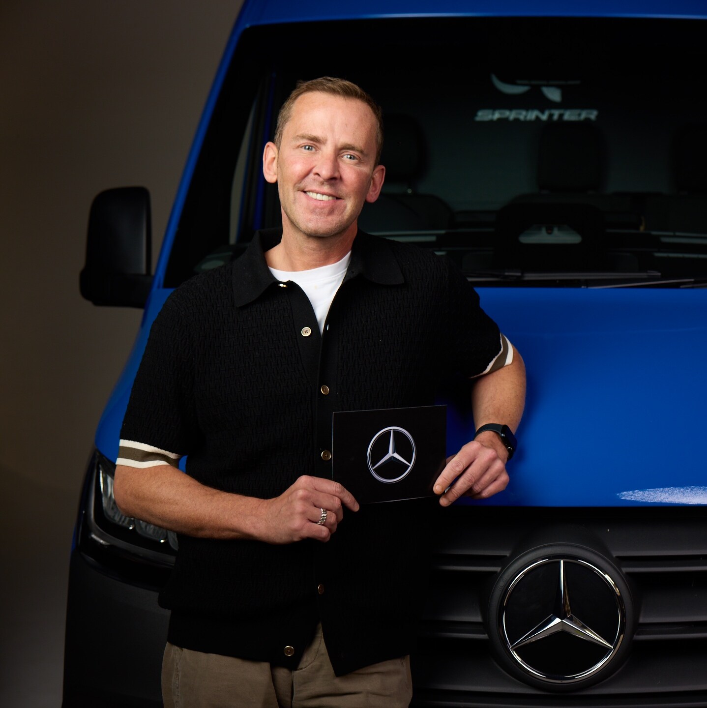 Close-up of the bonnet of a Mercedes-Benz eSprinter, showing the van plugged in and charging in a parking space.