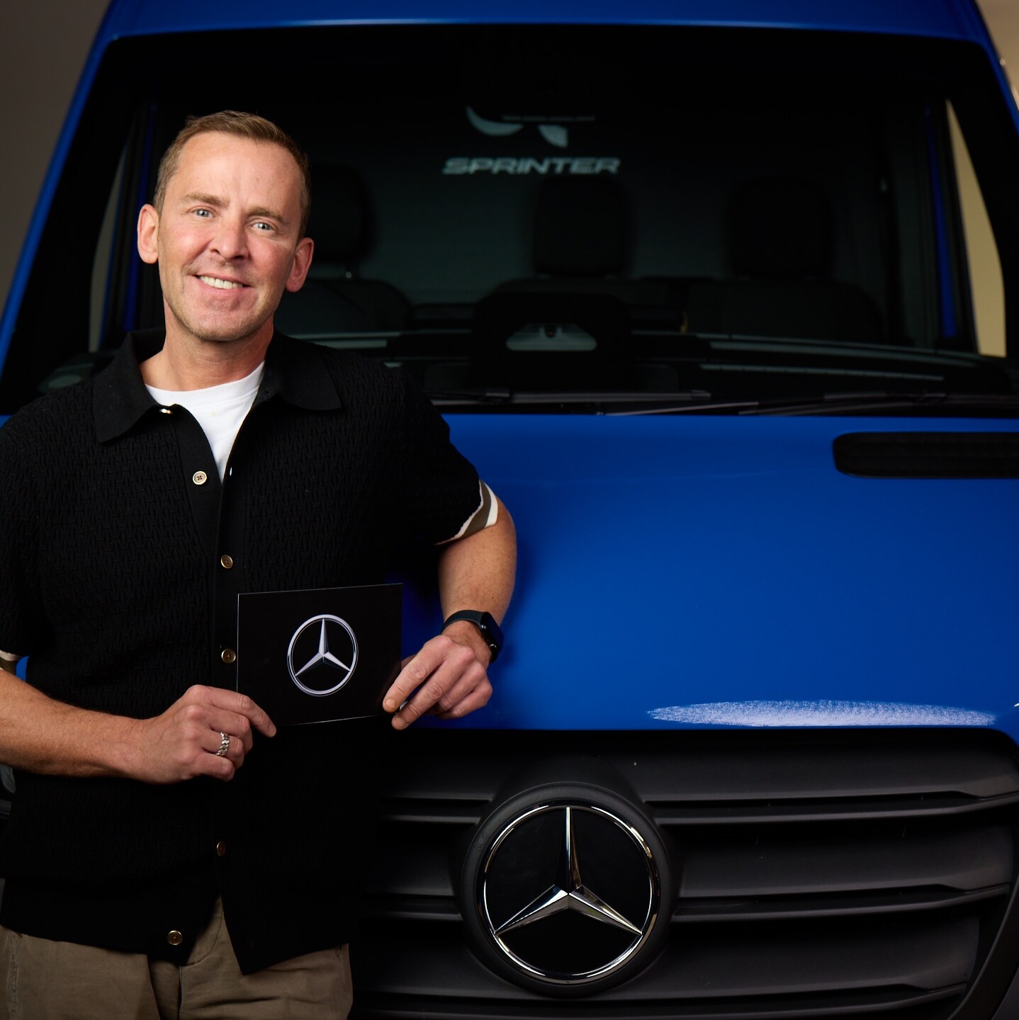 Close-up of the bonnet of a Mercedes-Benz eSprinter, showing the van plugged in and charging in a parking space.