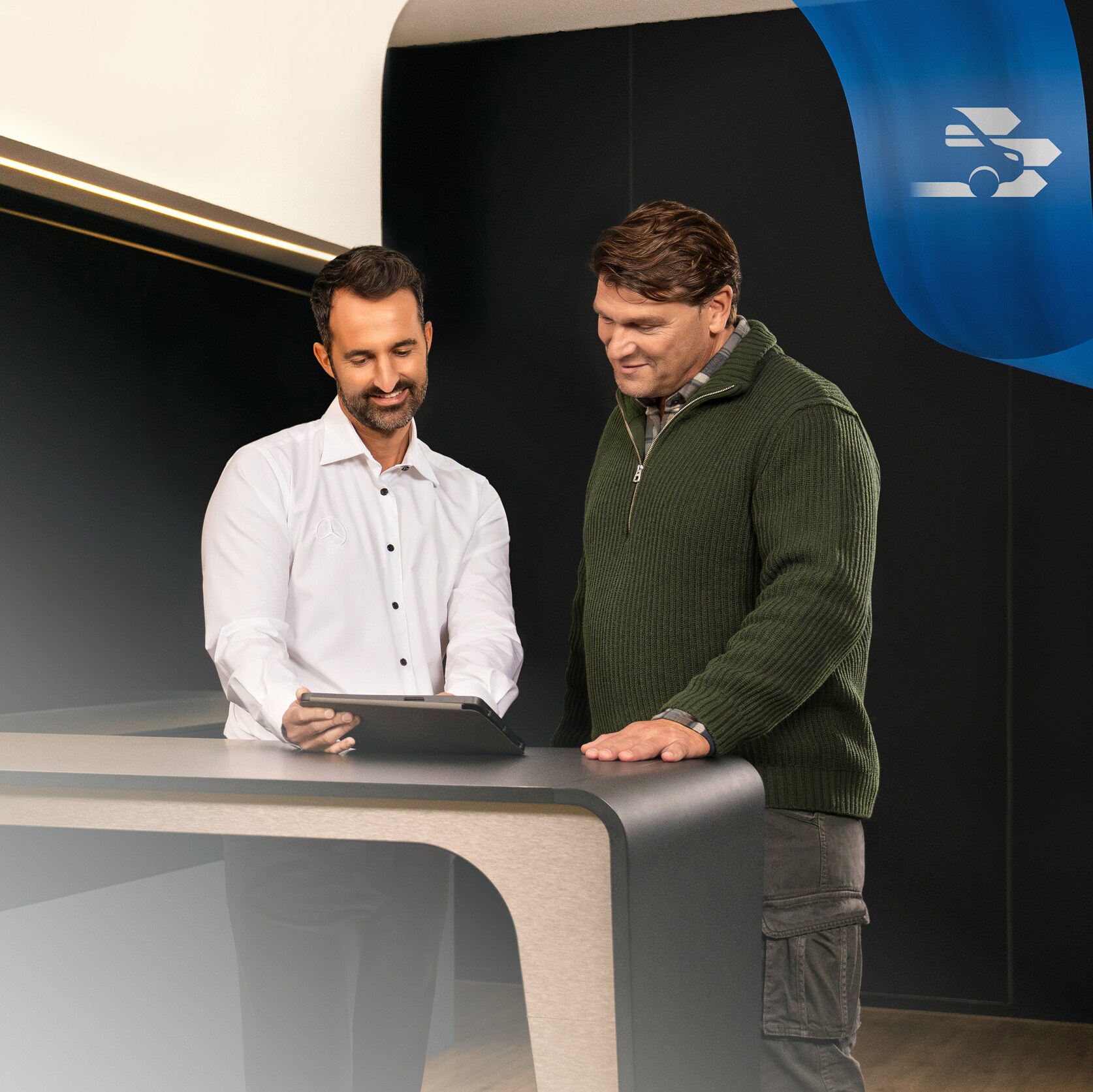 Two Men standing in a Mercedes-Benz Authorised Repairer office, discussing something seen on a Tablet
