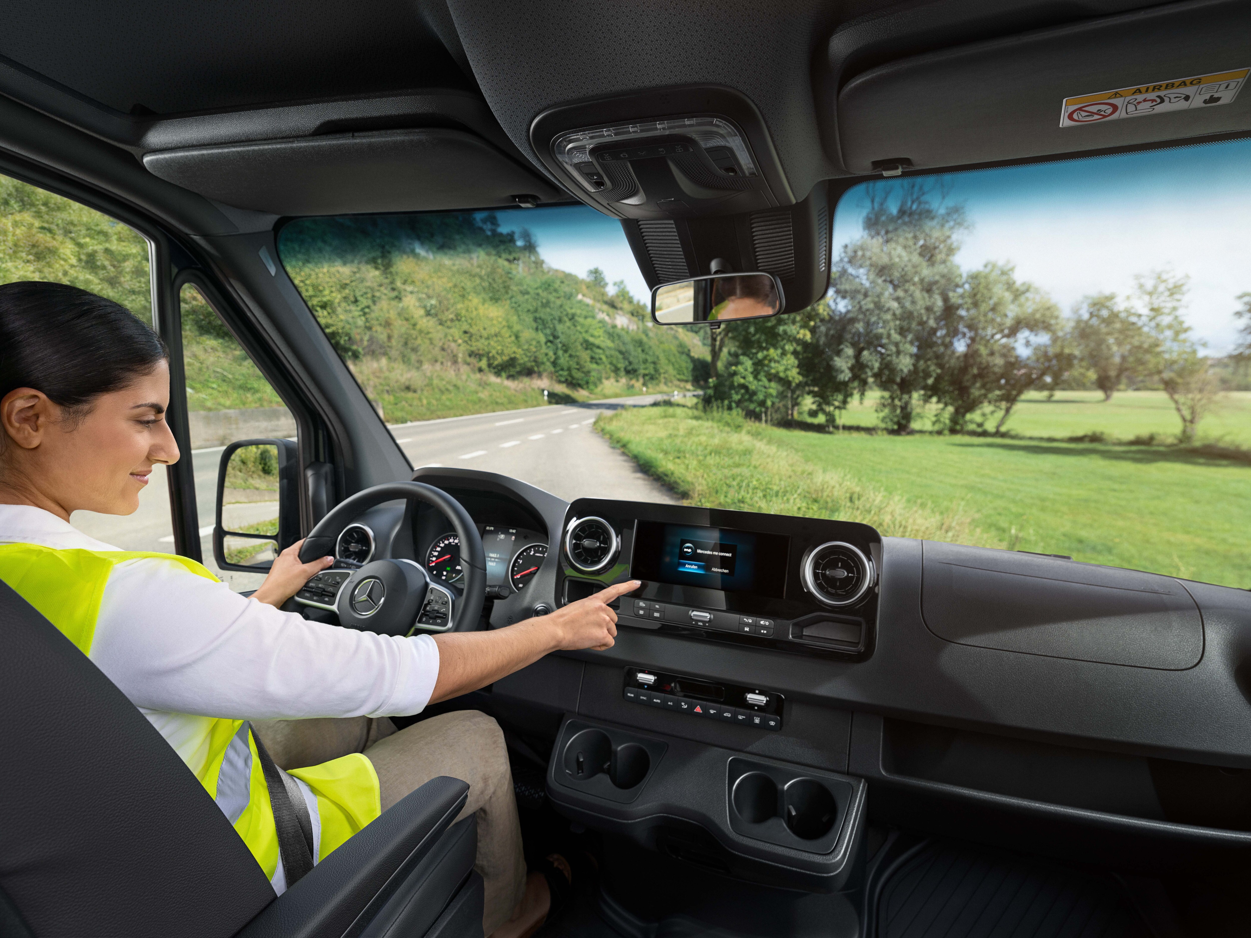 Driver using the MBUX multimedia system inside a Mercedes-Benz van cockpit