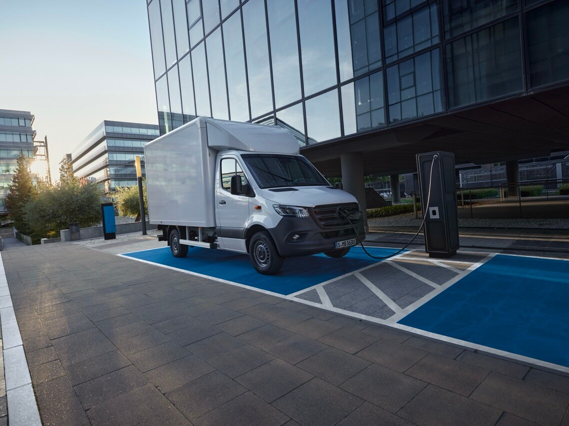 White Mercedes-Benz eSprinter luton box van parked by a charger.