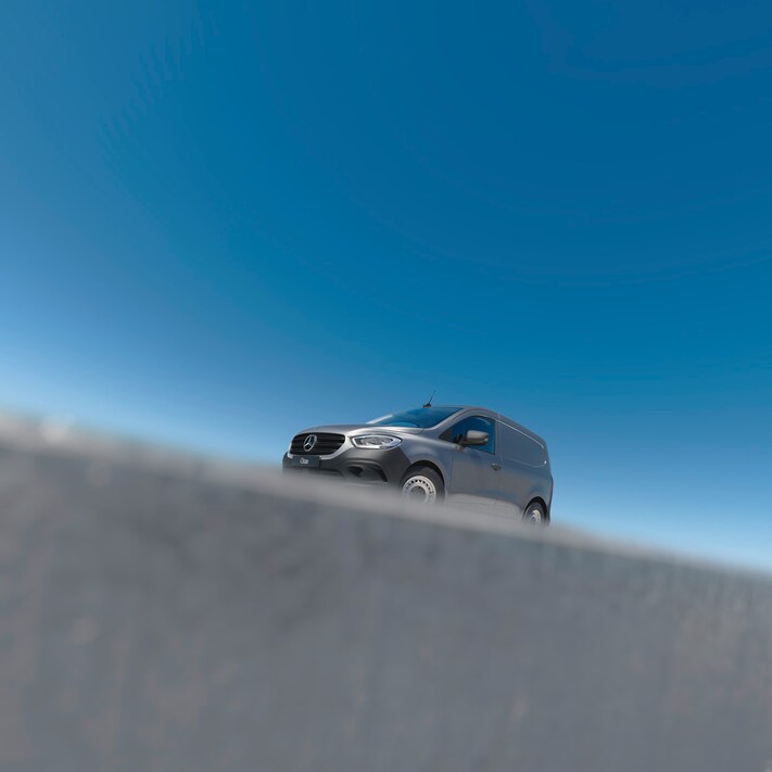 Close-up of the bonnet of a Mercedes-Benz eSprinter, showing the van plugged in and charging in a parking space.