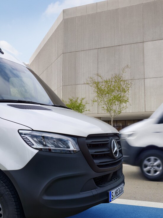 Two white Mercedes-Benz Sprinter vans on the move.
