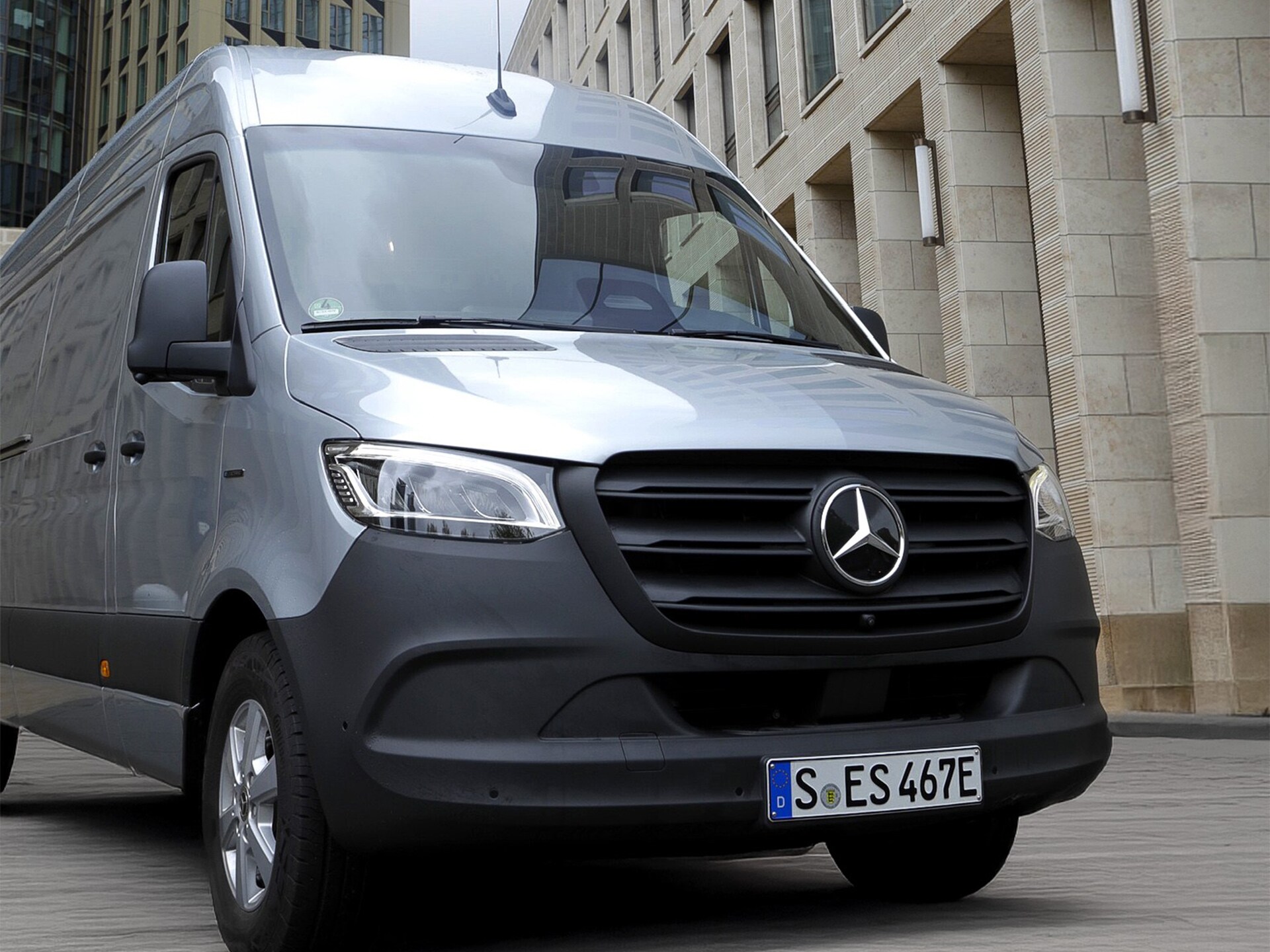 Silver Mercedes-Benz Sprinter van parked on a city street, showcasing front grille with prominent Mercedes logo.